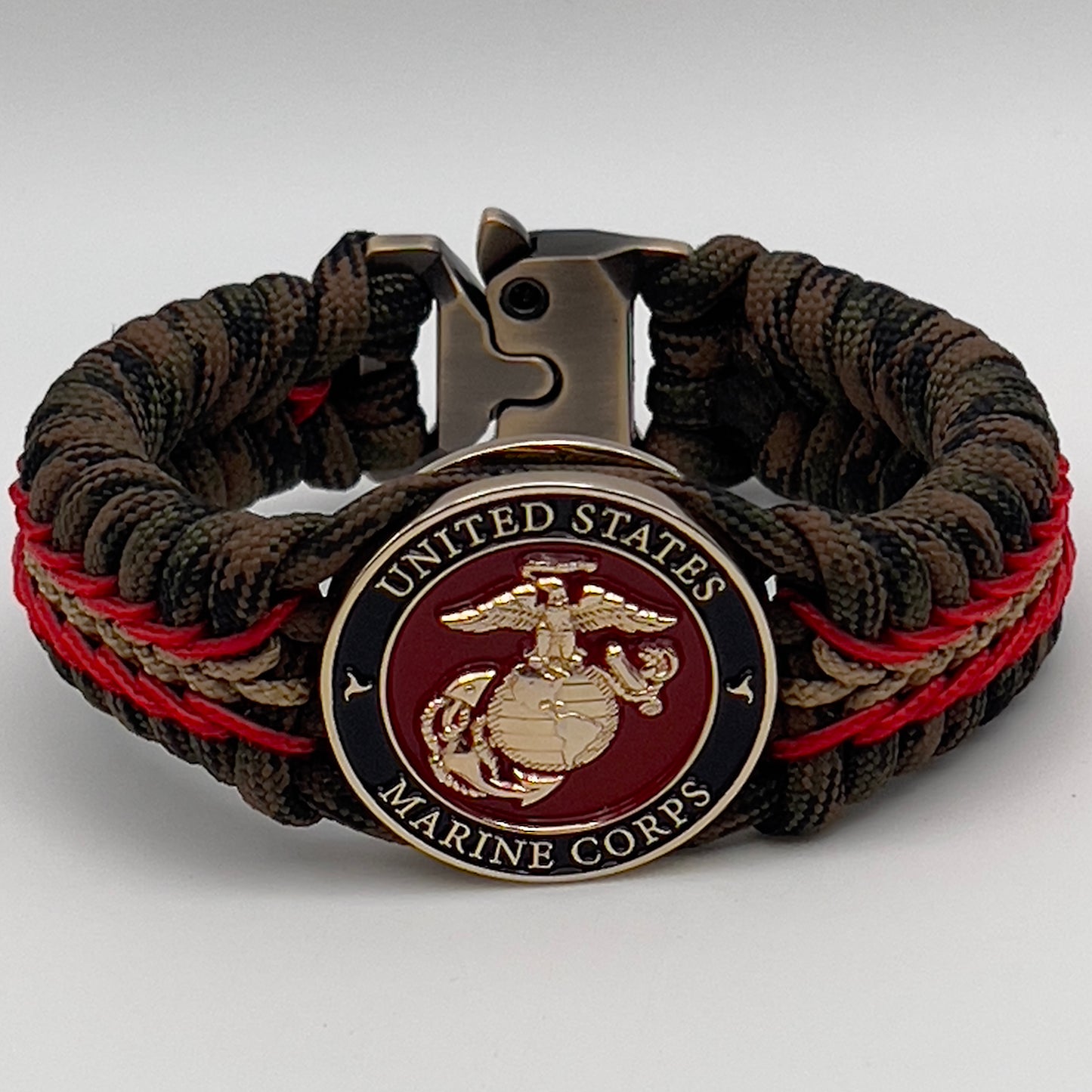 Thick, rigid and comfortable braided United States Marine Corps bracelet featuring a 24K gold plated USMC Eagle Globe and Anchor medallion, a gold Cobra style tactical buckle and woven with Woodland camo 550 paracord and Imperial Red and Gold micro cord.