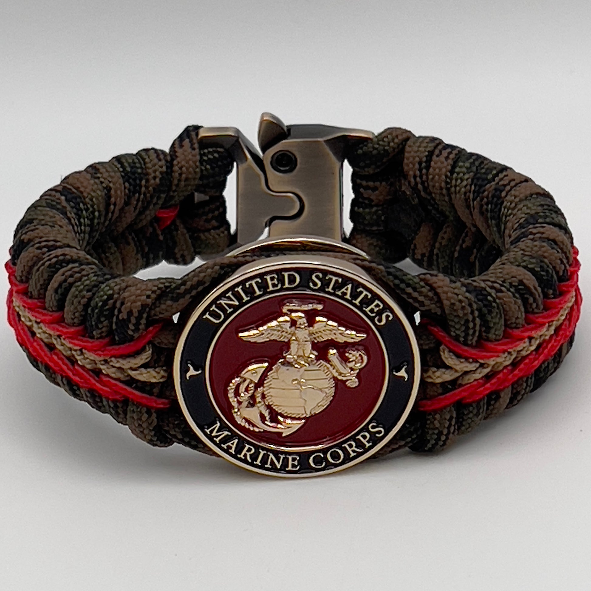 Thick, rigid and comfortable braided United States Marine Corps bracelet featuring a 24K gold plated USMC Eagle Globe and Anchor medallion, a gold Cobra style tactical buckle and woven with Woodland camo 550 paracord and Imperial Red and Gold micro cord.