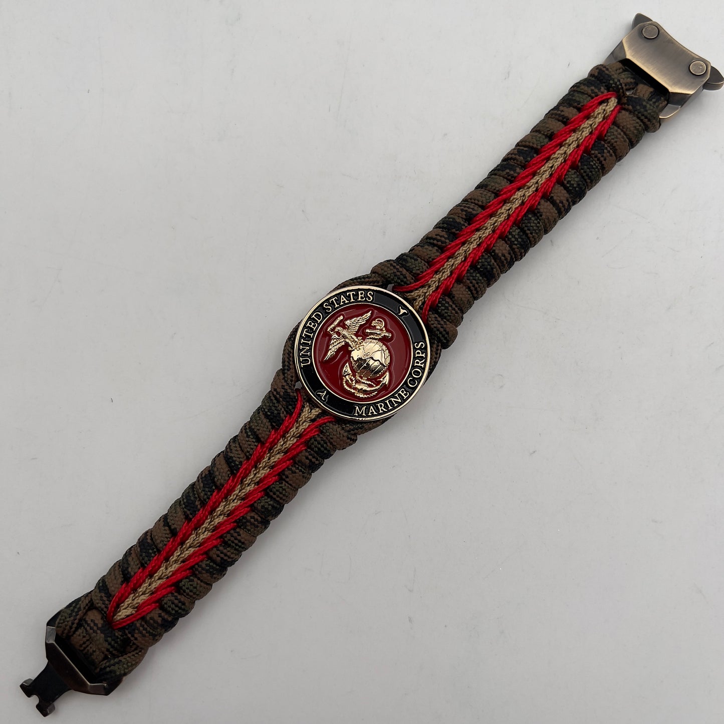 Thick, rigid and comfortable braided United States Marine Corps bracelet featuring a 24K gold plated USMC Eagle Globe and Anchor medallion, a gold Cobra style tactical buckle and woven with Woodland camo 550 paracord and Imperial Red and Gold micro cord.