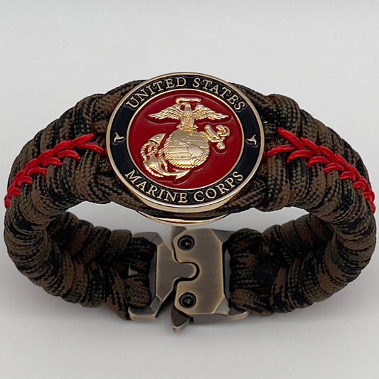 Thick, rigid and comfortable braided United States Marine Corps bracelet featuring a 24K gold plated USMC Eagle Globe and Anchor medallion, a gold Cobra style tactical buckle and woven with Woodland Camo 550 paracord and Imperial Red micro cord.