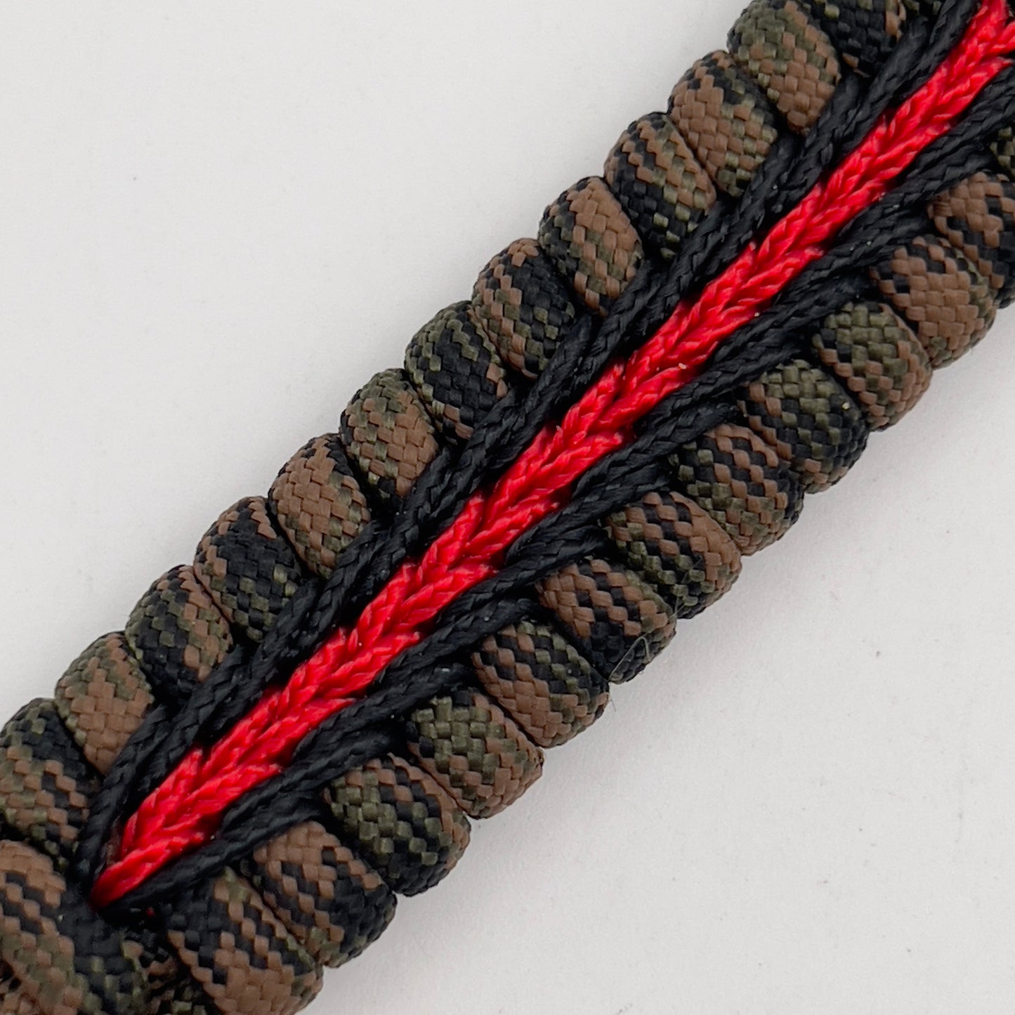Thick, semi-rigid and comfortable braided United States Marine Corps bracelet featuring a 24K gold plated USMC Eagle Globe and Anchor medallion, a gold Cobra style tactical buckle and woven with Woodland camo 550 paracord and black and Imperial red micro cord.