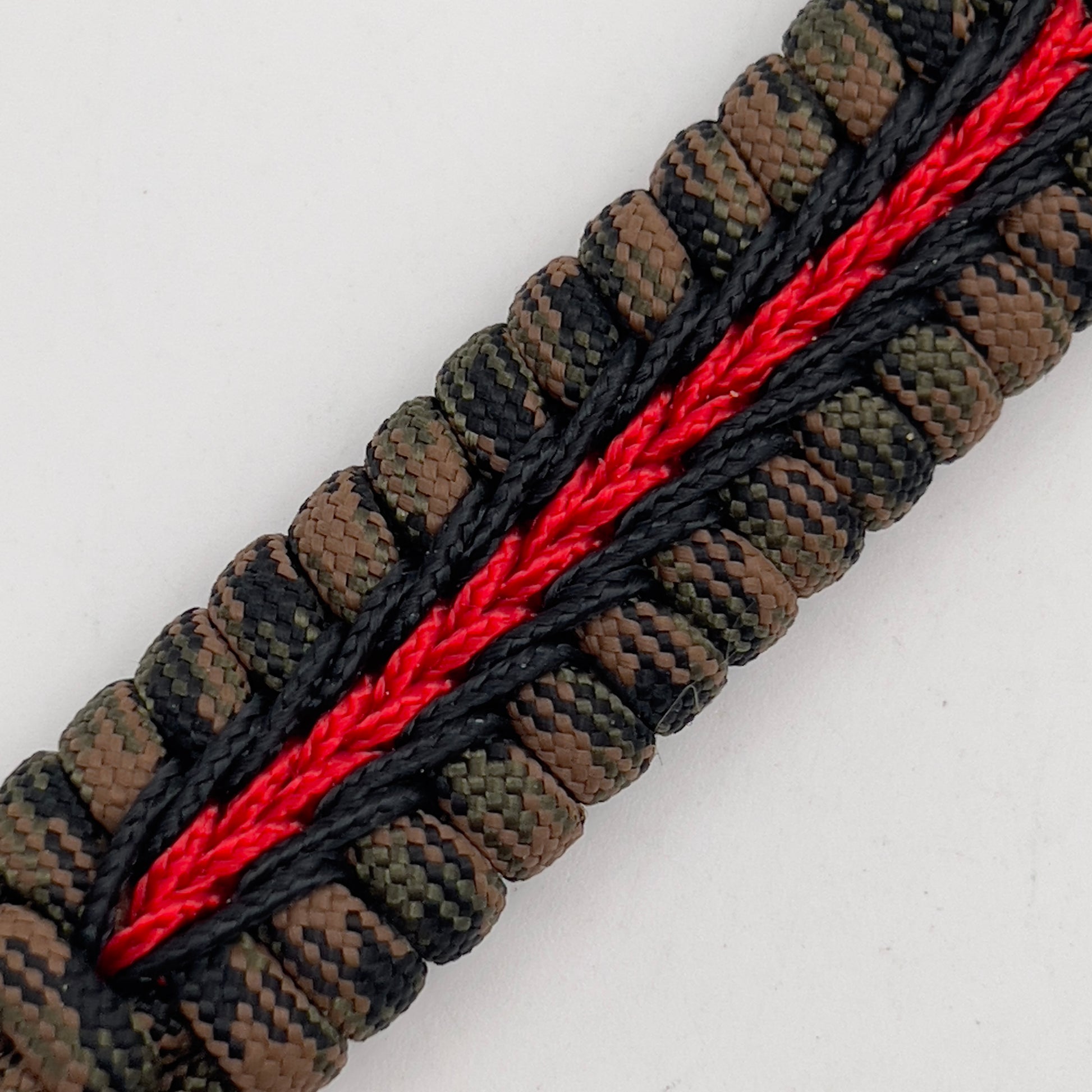 Thick, semi-rigid and comfortable braided United States Marine Corps bracelet featuring a 24K gold plated USMC Eagle Globe and Anchor medallion, a gold Cobra style tactical buckle and woven with Woodland camo 550 paracord and black and Imperial red micro cord.