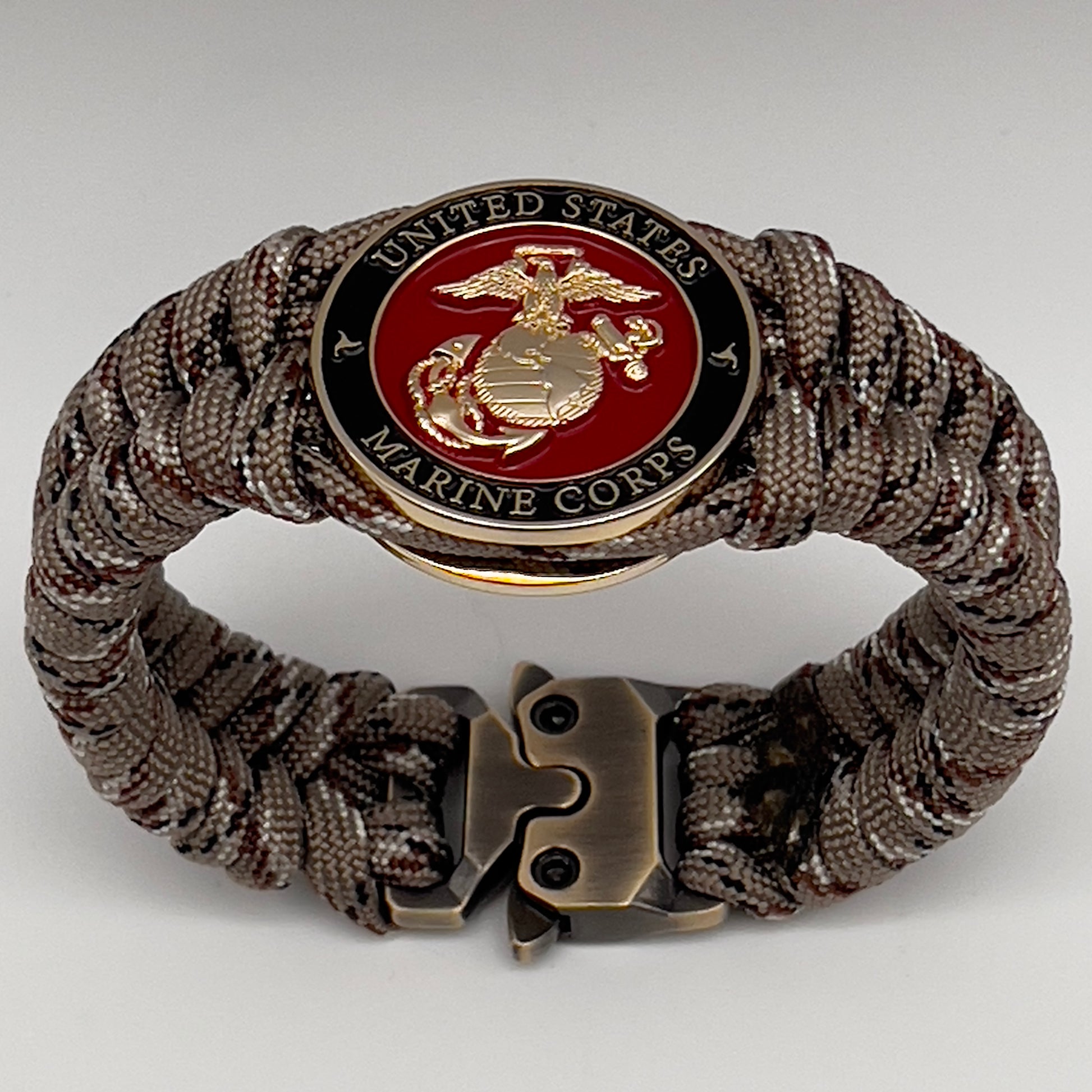 Thick, semi-rigid and comfortable braided United States Marine Corps bracelet featuring a 24K gold plated USMC Eagle Globe and Anchor medallion, a gold Cobra style tactical buckle and woven with Desert Camo 550 paracord.
