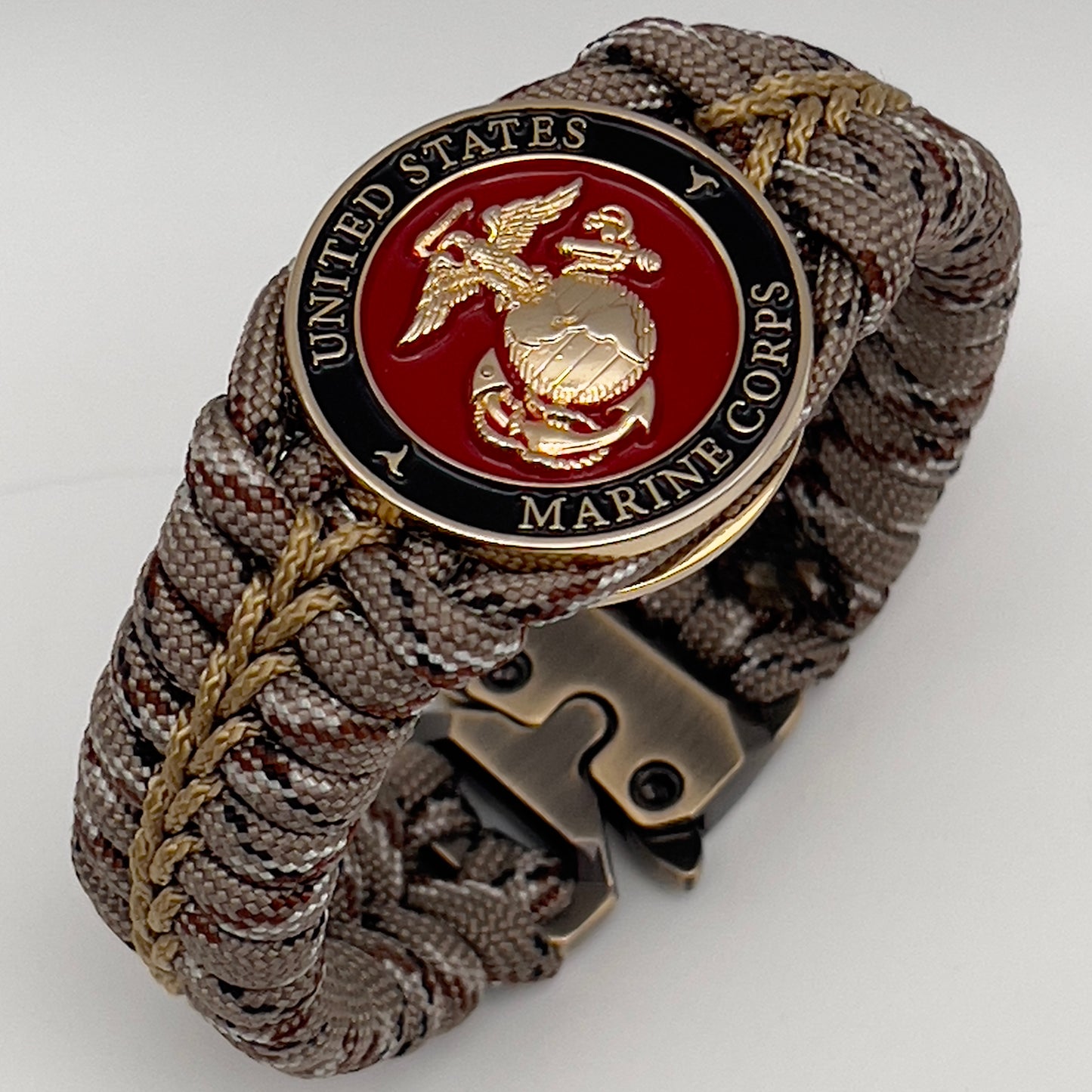 Thick, rigid and comfortable braided United States Marine Corps bracelet featuring a 24K gold plated USMC Eagle Globe and Anchor medallion, a gold Cobra style tactical buckle and woven with Desert Camo 550 paracord.