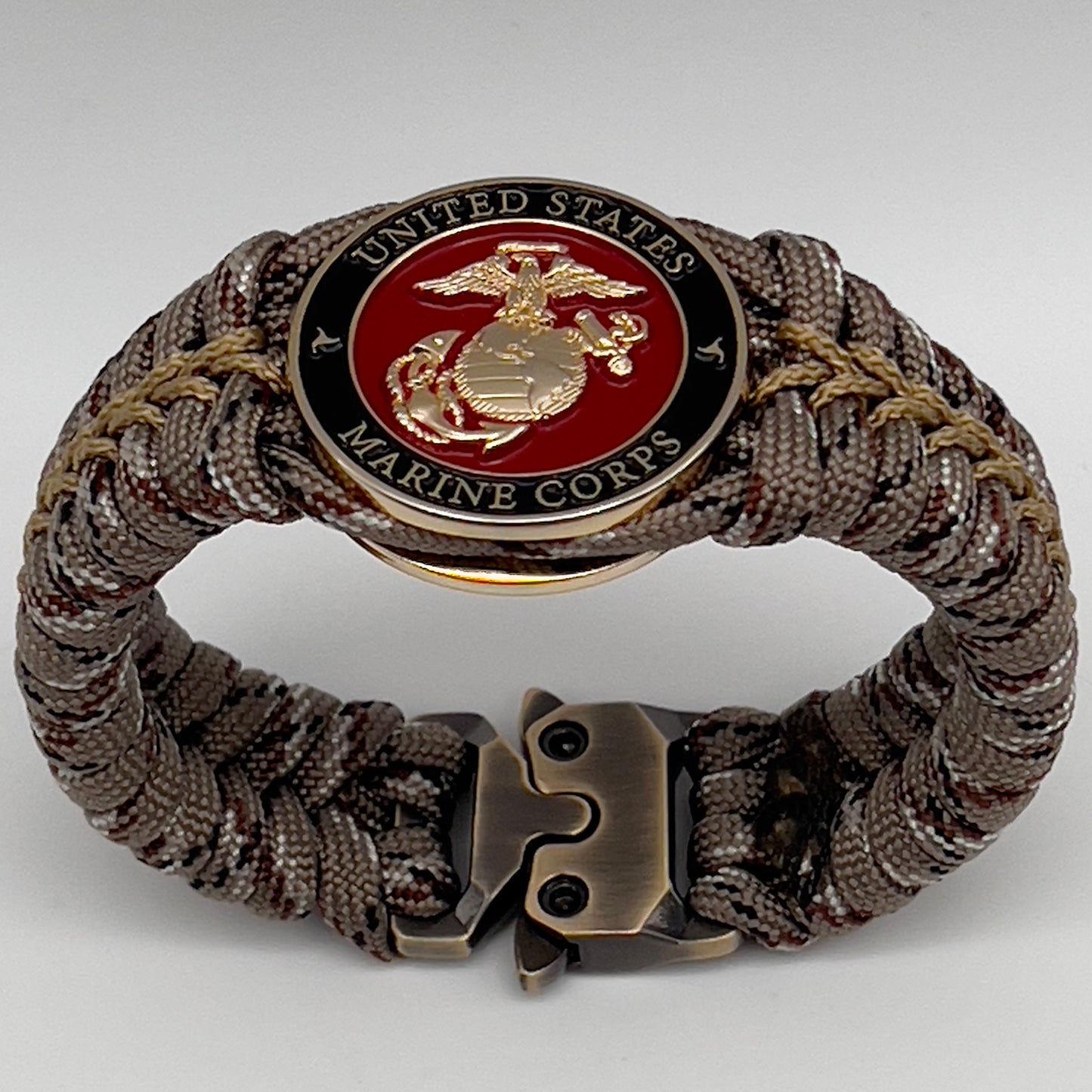 Thick, rigid and comfortable braided United States Marine Corps bracelet featuring a 24K gold plated USMC Eagle Globe and Anchor medallion, a gold Cobra style tactical buckle and woven with Desert Camo 550 paracord.