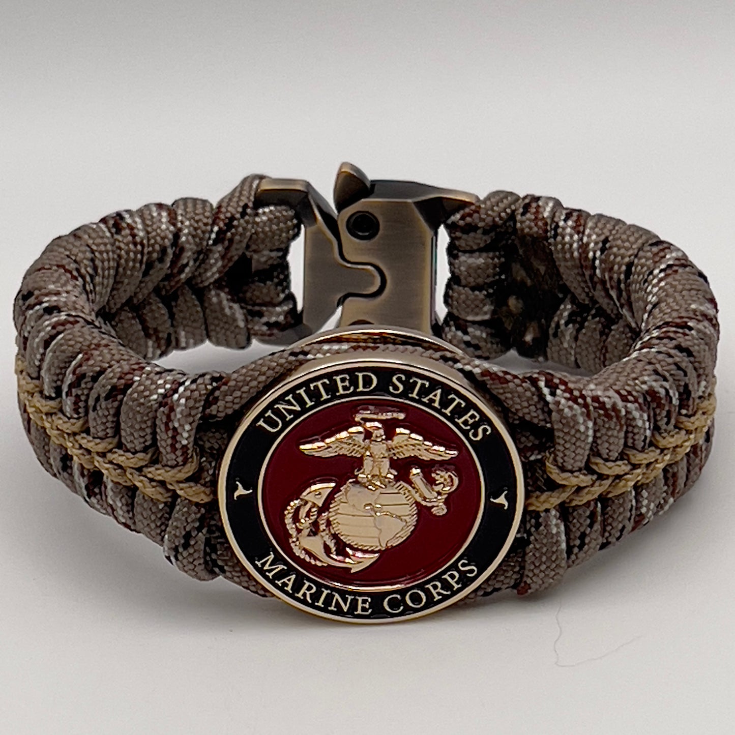 Thick, rigid and comfortable braided United States Marine Corps bracelet featuring a 24K gold plated USMC Eagle Globe and Anchor medallion, a gold Cobra style tactical buckle and woven with Desert Camo 550 paracord.