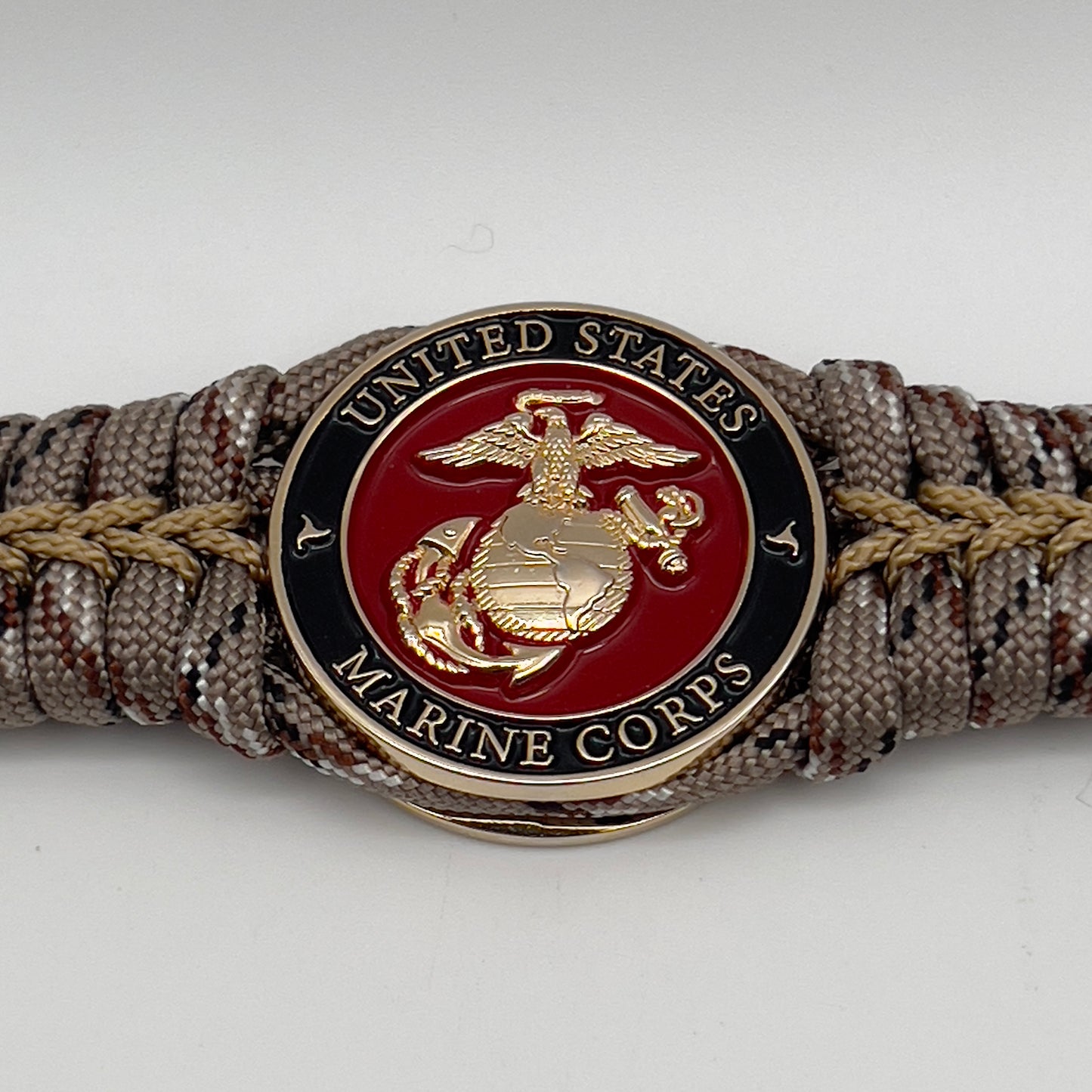 Thick, rigid and comfortable braided United States Marine Corps bracelet featuring a 24K gold plated USMC Eagle Globe and Anchor medallion, a gold Cobra style tactical buckle and woven with Desert Camo 550 paracord.