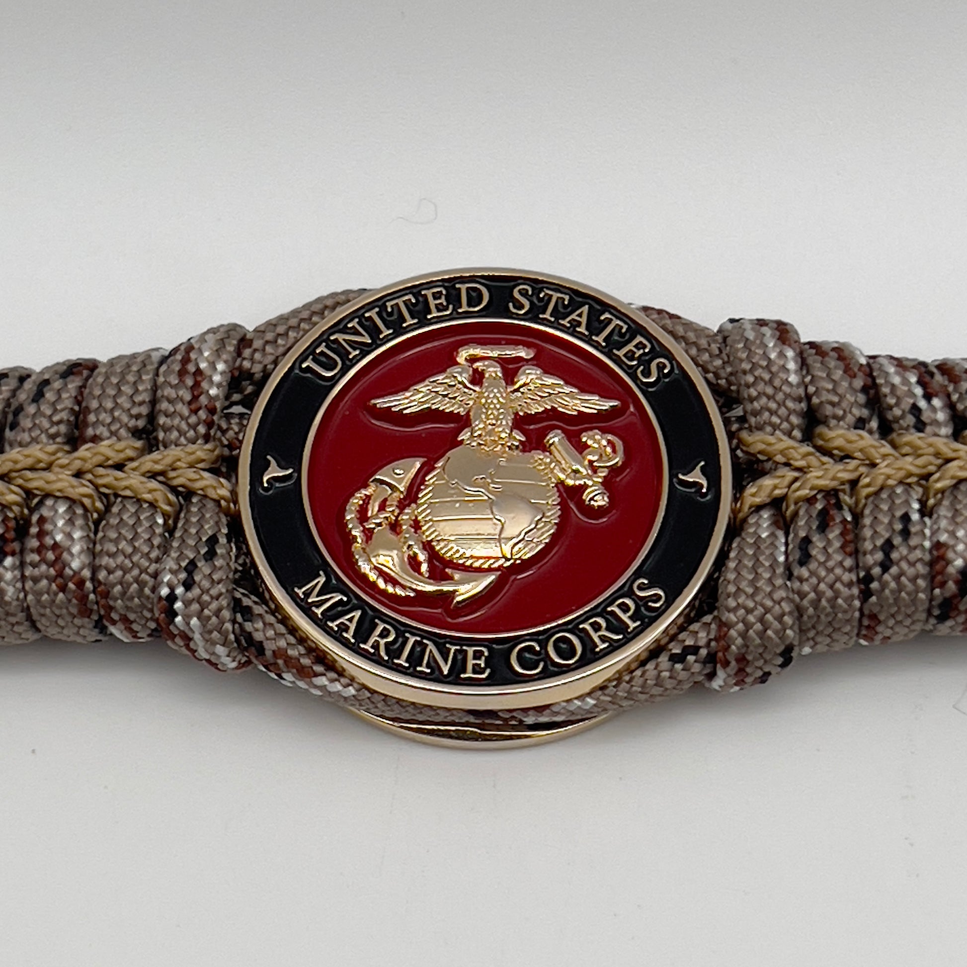 Thick, rigid and comfortable braided United States Marine Corps bracelet featuring a 24K gold plated USMC Eagle Globe and Anchor medallion, a gold Cobra style tactical buckle and woven with Desert Camo 550 paracord.