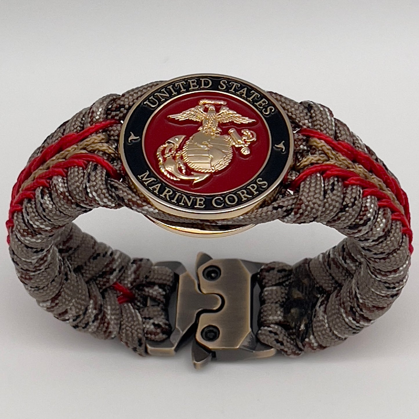 Thick, rigid and comfortable braided United States Marine Corps bracelet featuring a 24K gold plated USMC Eagle Globe and Anchor medallion, a gold Cobra style tactical buckle and woven with Desert Camo 550 paracord and Imperial Red and Gold micro cord.