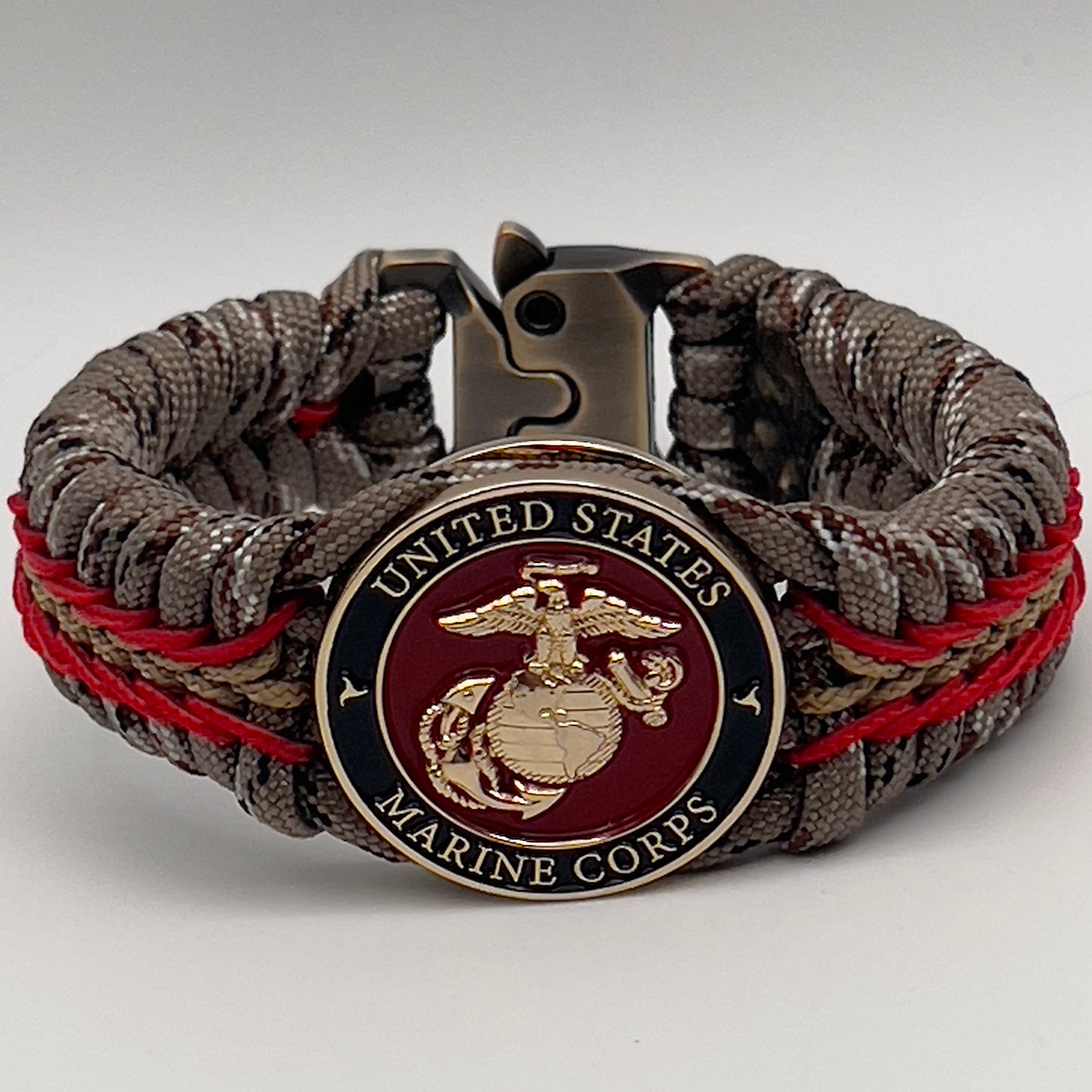 Thick, rigid and comfortable braided United States Marine Corps bracelet featuring a 24K gold plated USMC Eagle Globe and Anchor medallion, a gold Cobra style tactical buckle and woven with Desert Camo 550 paracord and Imperial Red and Gold micro cord.