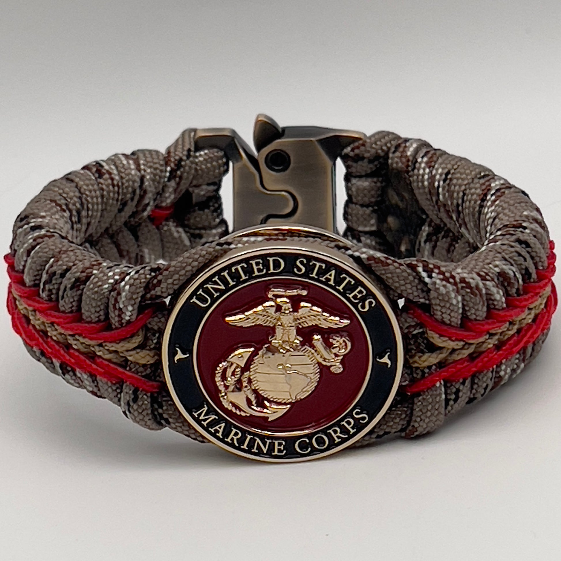 Thick, rigid and comfortable braided United States Marine Corps bracelet featuring a 24K gold plated USMC Eagle Globe and Anchor medallion, a gold Cobra style tactical buckle and woven with Desert Camo 550 paracord and Imperial Red and Gold micro cord.