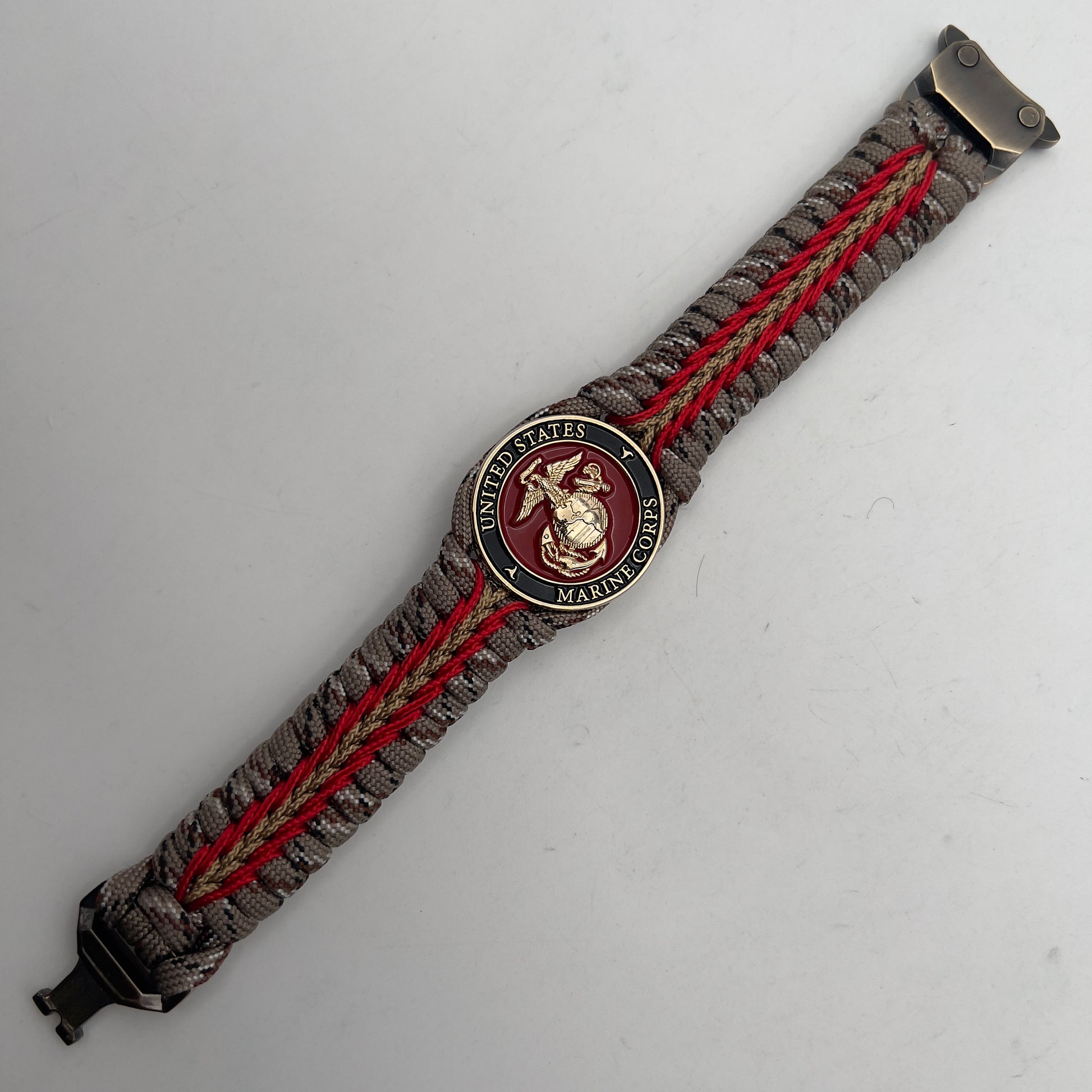 Thick, rigid and comfortable braided United States Marine Corps bracelet featuring a 24K gold plated USMC Eagle Globe and Anchor medallion, a gold Cobra style tactical buckle and woven with Desert Camo 550 paracord and Imperial Red and Gold micro cord.
