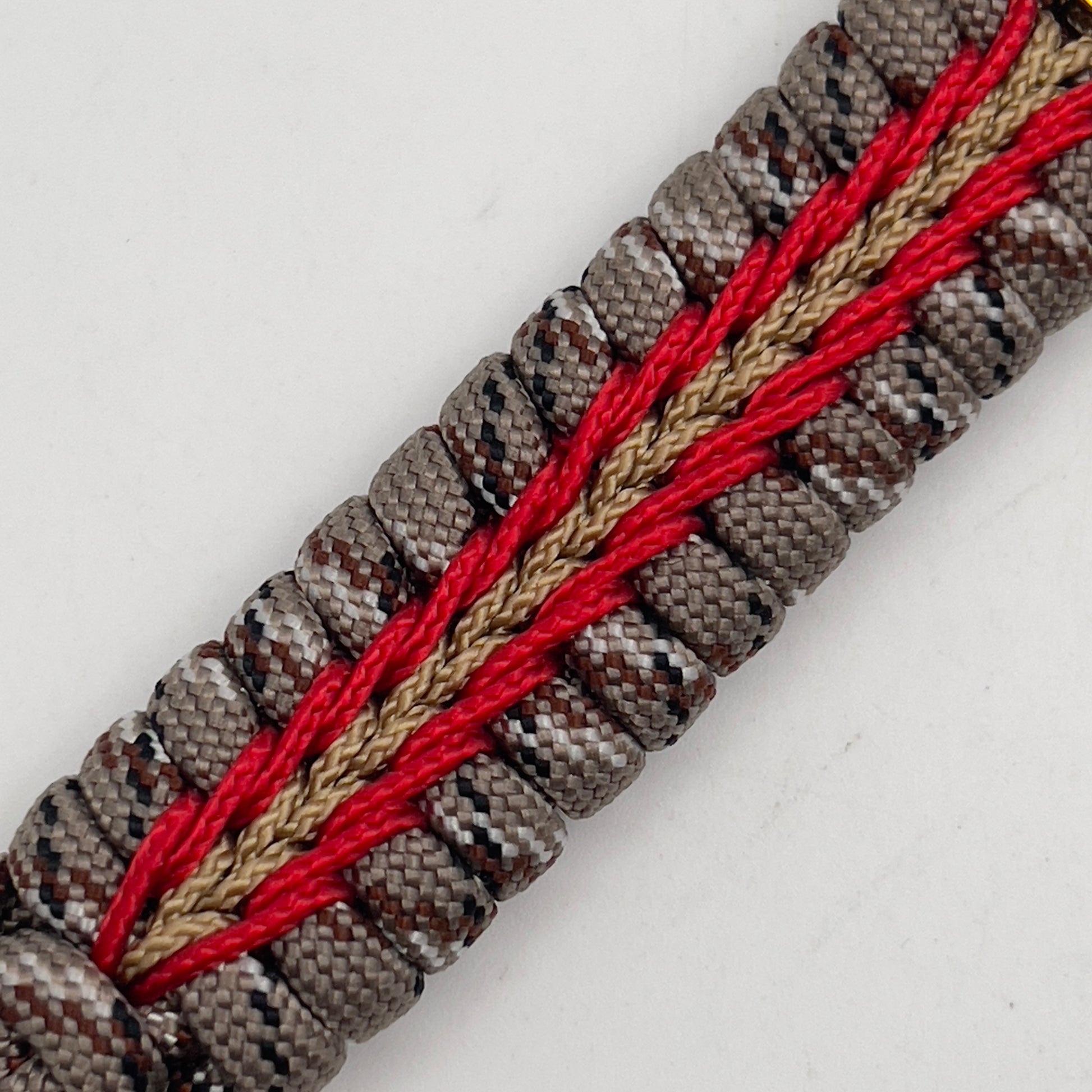 Thick, rigid and comfortable braided United States Marine Corps bracelet featuring a 24K gold plated USMC Eagle Globe and Anchor medallion, a gold Cobra style tactical buckle and woven with Desert Camo 550 paracord and Imperial Red and Gold micro cord.