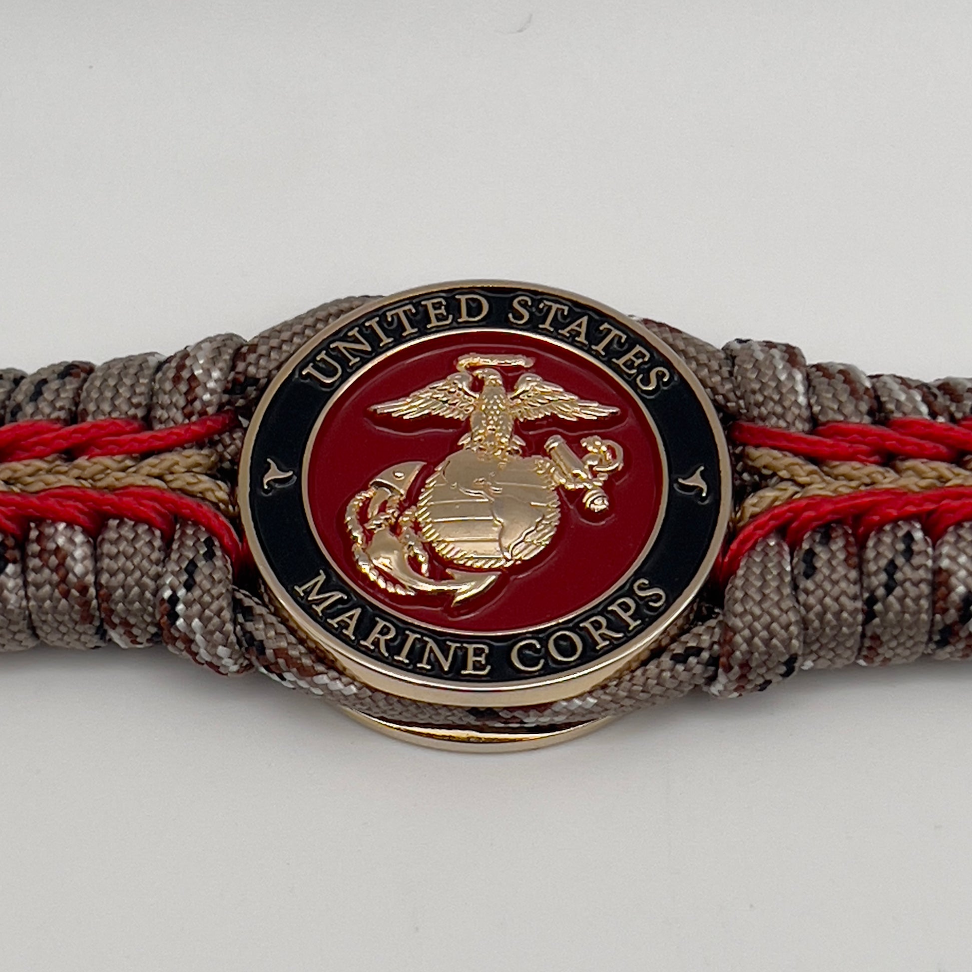 Thick, rigid and comfortable braided United States Marine Corps bracelet featuring a 24K gold plated USMC Eagle Globe and Anchor medallion, a gold Cobra style tactical buckle and woven with Desert Camo 550 paracord and Imperial Red and Gold micro cord.