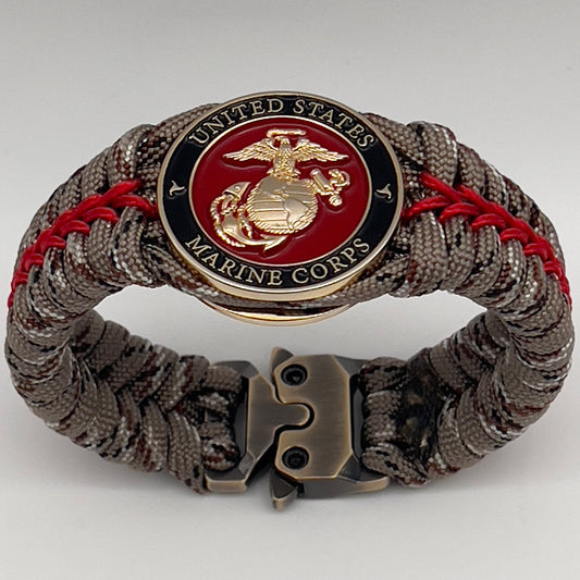 Thick, rigid and comfortable braided United States Marine Corps bracelet featuring a 24K gold plated USMC Eagle Globe and Anchor medallion, a gold Cobra style tactical buckle and woven with Desert Camo 550 paracord and Imperial Red micro cord.