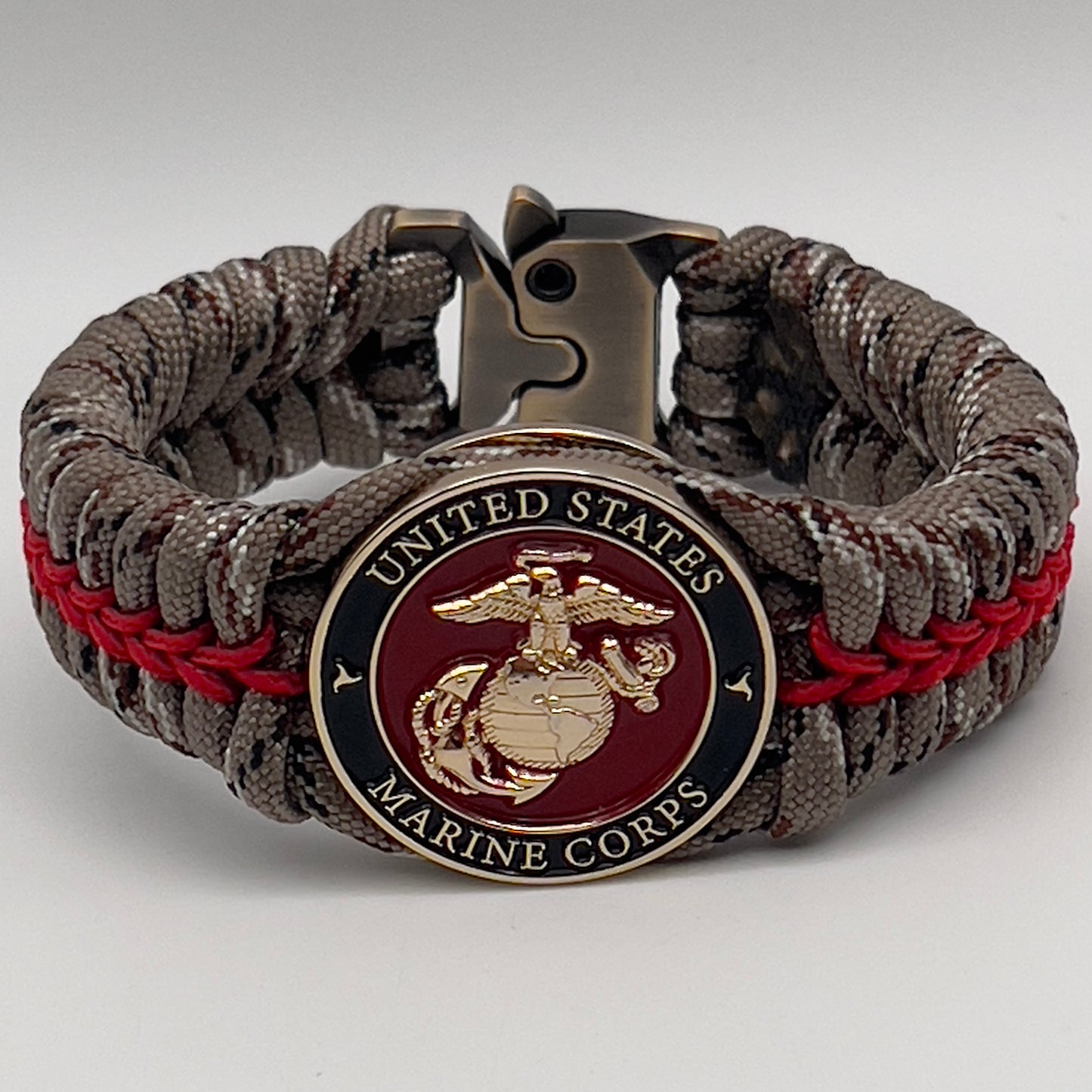Thick, rigid and comfortable braided United States Marine Corps bracelet featuring a 24K gold plated USMC Eagle Globe and Anchor medallion, a gold Cobra style tactical buckle and woven with Desert Camo 550 paracord and Imperial Red micro cord.