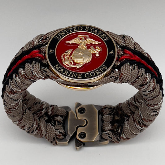 Thick, rigid and comfortable braided United States Marine Corps bracelet featuring a 24K gold plated USMC Eagle Globe and Anchor medallion, a gold Cobra style tactical buckle and woven with Desert Camo 550 paracord and black and Imperial Red micro cord.
