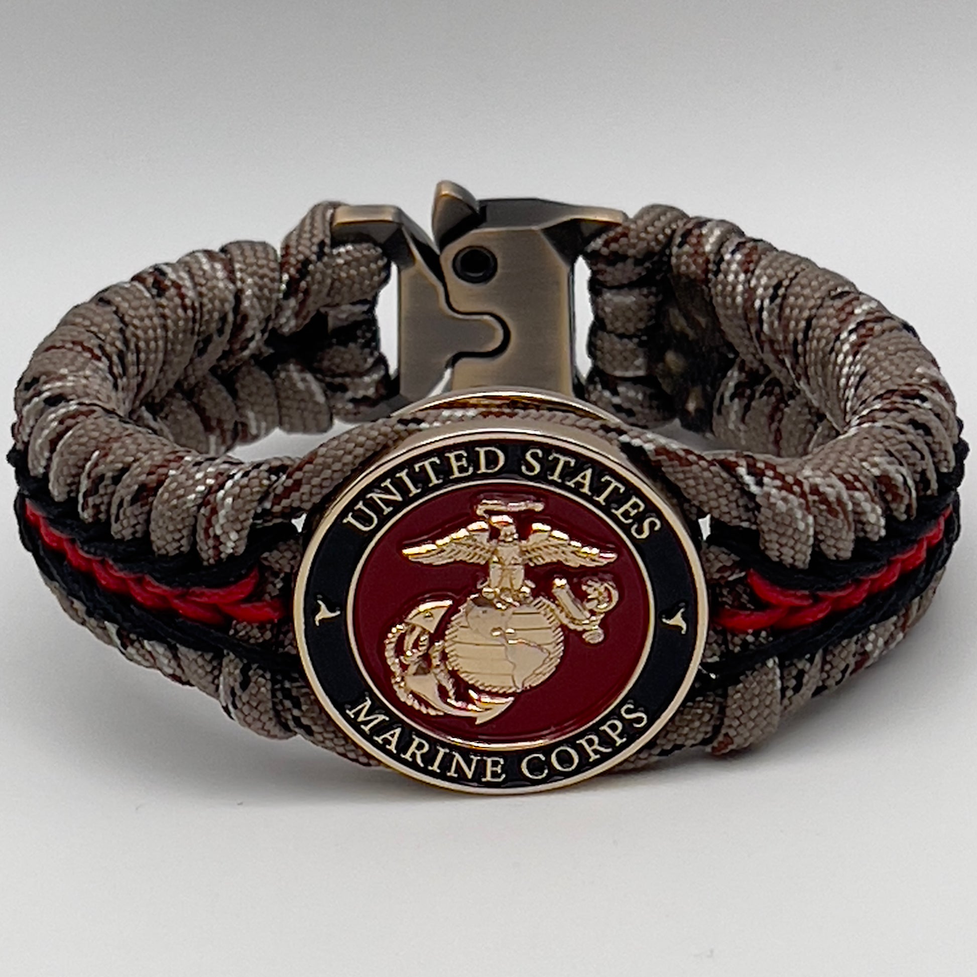 Thick, rigid and comfortable braided United States Marine Corps bracelet featuring a 24K gold plated USMC Eagle Globe and Anchor medallion, a gold Cobra style tactical buckle and woven with Desert Camo 550 paracord and black and Imperial Red micro cord.
