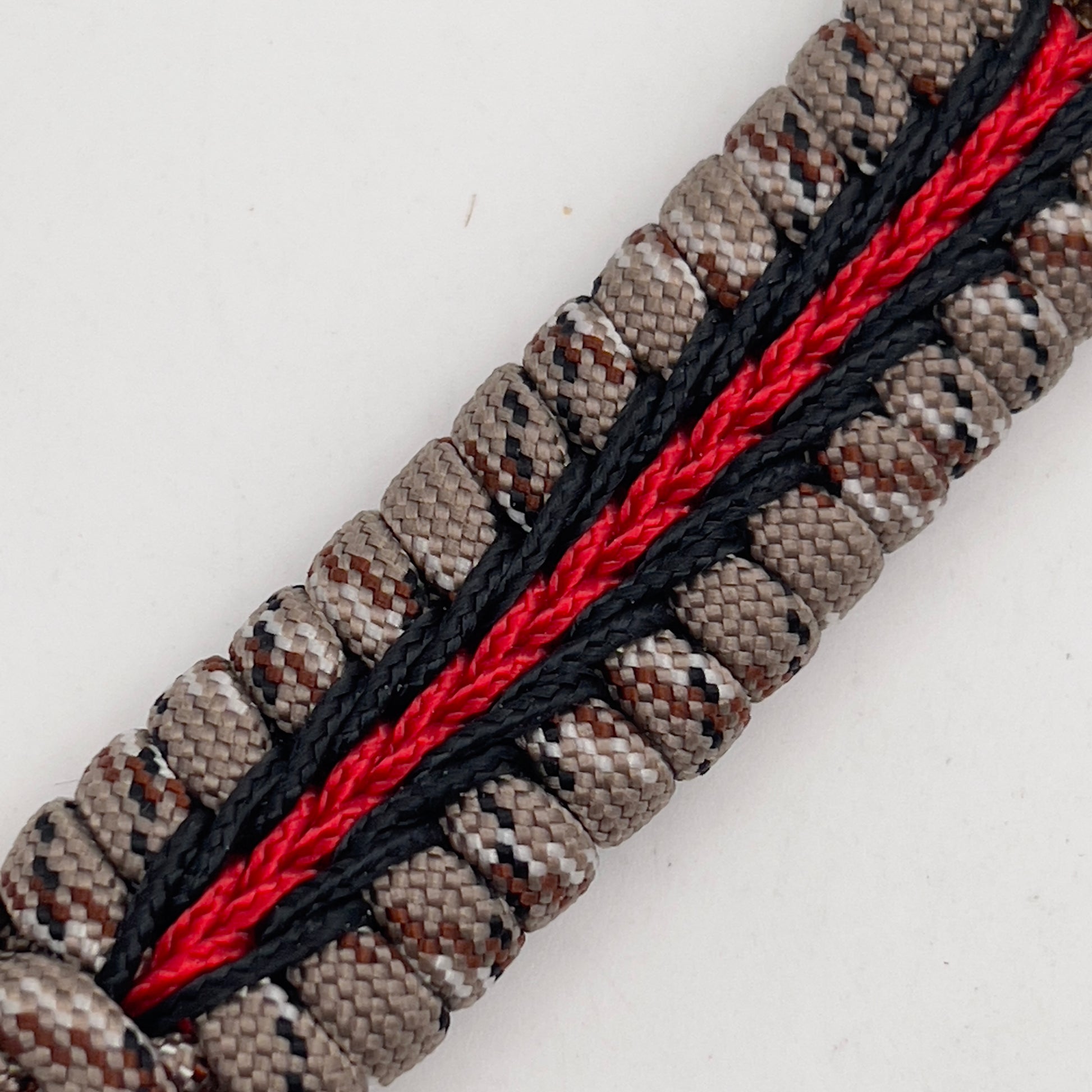 Thick, rigid and comfortable braided United States Marine Corps bracelet featuring a 24K gold plated USMC Eagle Globe and Anchor medallion, a gold Cobra style tactical buckle and woven with Desert Camo 550 paracord and black and Imperial Red micro cord.