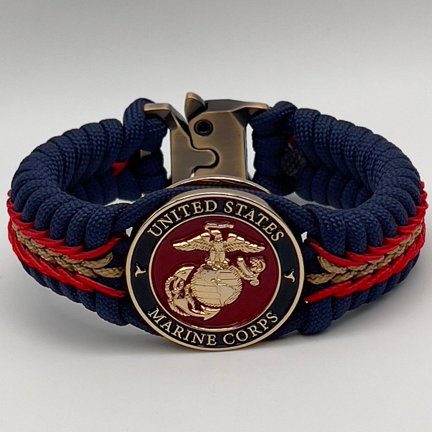 Thick, rigid and comfortable braided United States Marine Corps bracelet featuring a 24K gold plated USMC Eagle Globe and Anchor medallion, a gold Cobra style tactical buckle and woven with Navy Blue 550 paracord and Imperial Red and Gold micro cord.