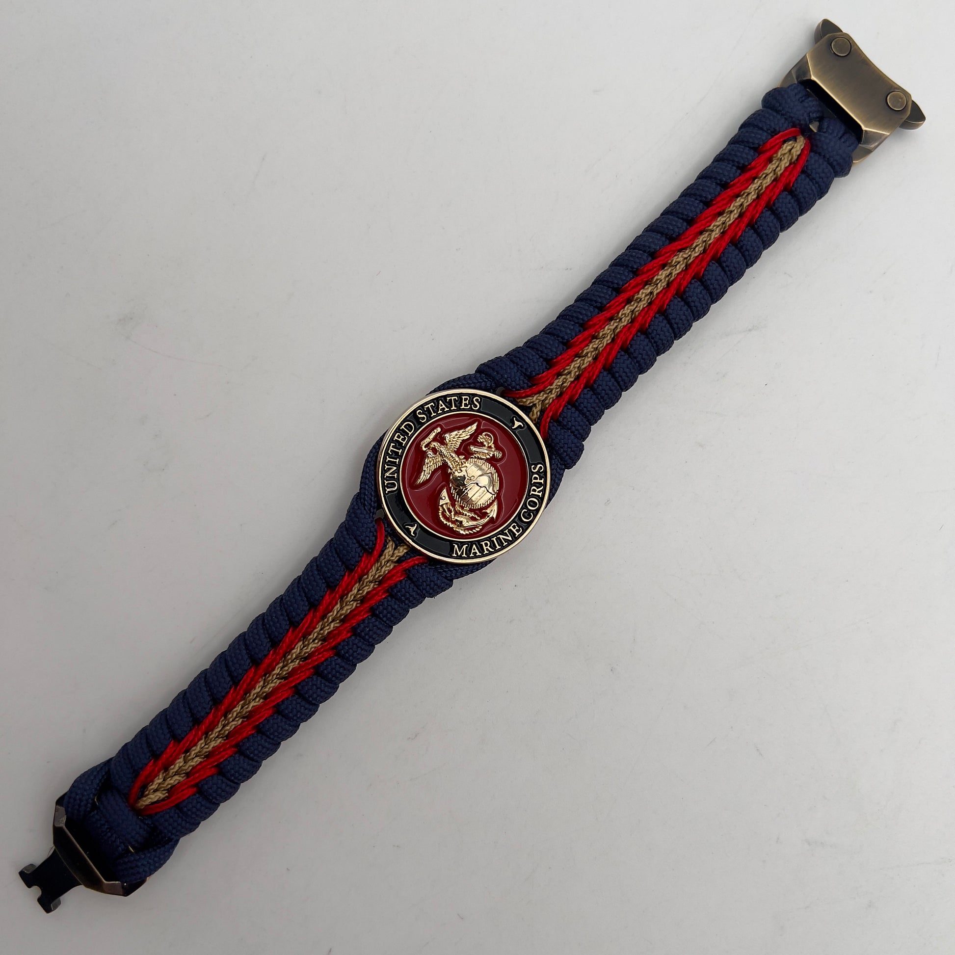 Thick, rigid and comfortable braided United States Marine Corps bracelet featuring a 24K gold plated USMC Eagle Globe and Anchor medallion, a gold Cobra style tactical buckle and woven with Navy Blue 550 paracord and Imperial Red and Gold micro cord.