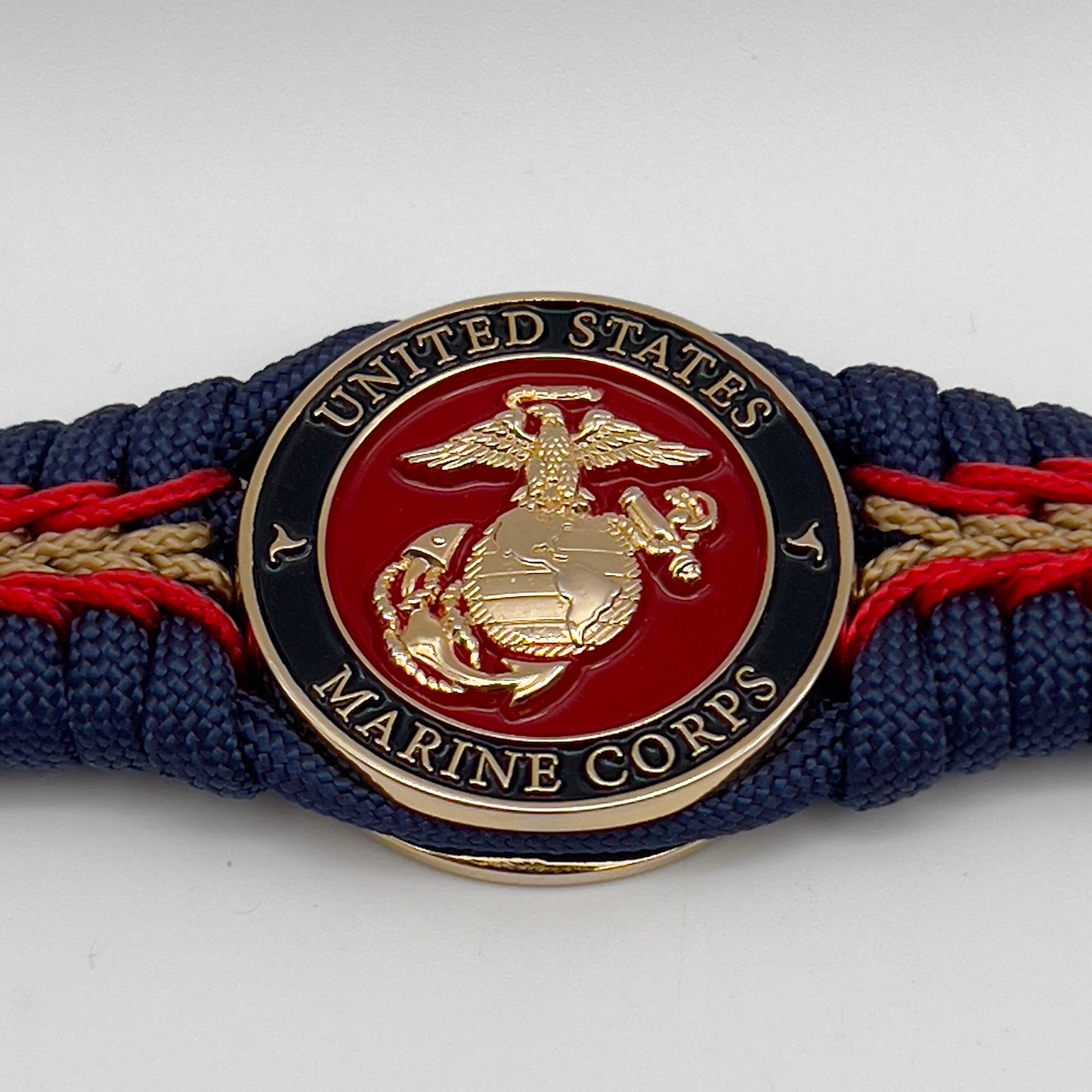 Thick, rigid and comfortable braided United States Marine Corps bracelet featuring a 24K gold plated USMC Eagle Globe and Anchor medallion, a gold Cobra style tactical buckle and woven with Navy Blue 550 paracord and Imperial Red and Gold micro cord.