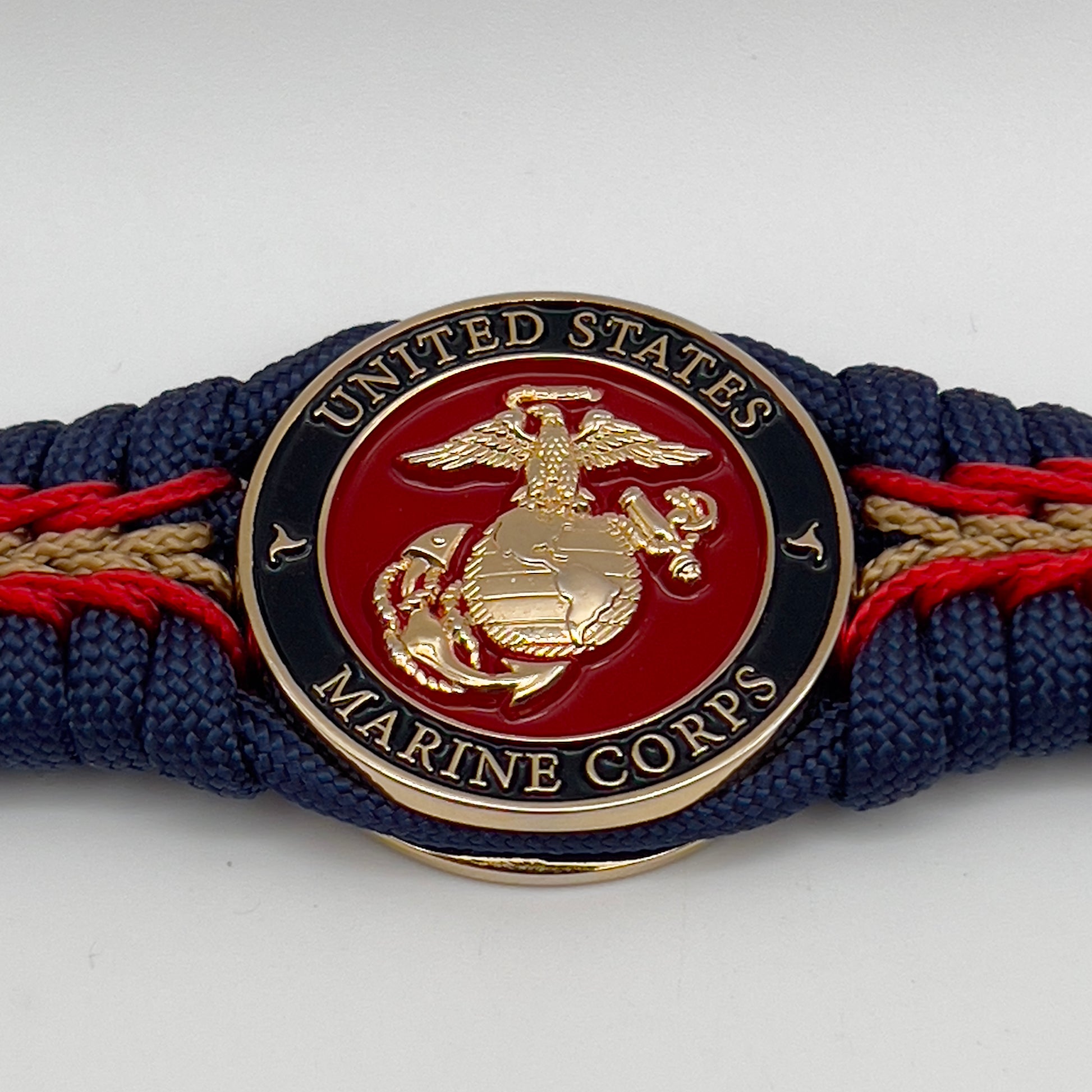 Thick, rigid and comfortable braided United States Marine Corps bracelet featuring a 24K gold plated USMC Eagle Globe and Anchor medallion, a gold Cobra style tactical buckle and woven with Navy Blue 550 paracord and Imperial Red and Gold micro cord.