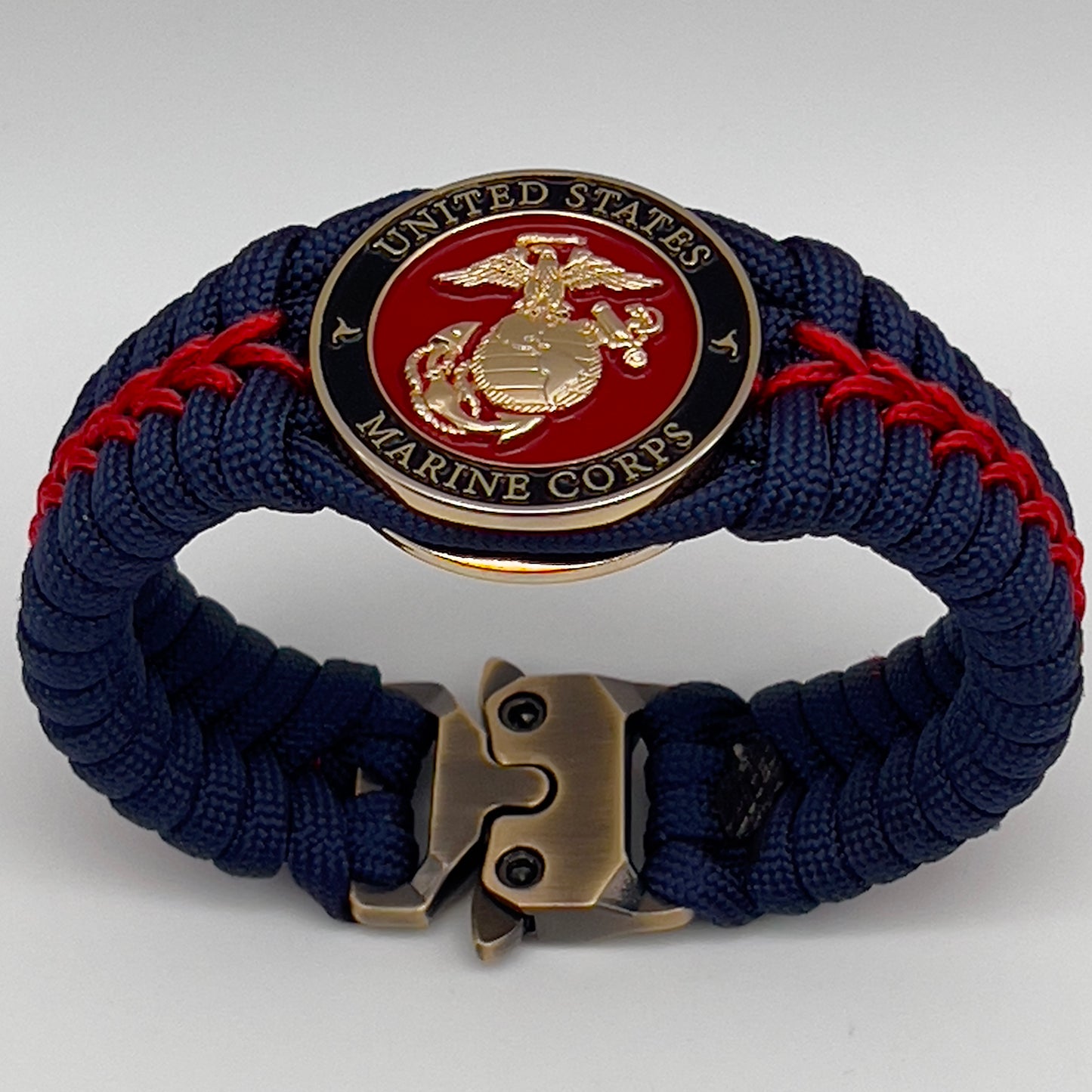 Thick, rigid and comfortable braided United States Marine Corps bracelet featuring a 24K gold plated USMC Eagle Globe and Anchor medallion, a gold Cobra style tactical buckle and woven withNavy Blue 550 paracord and Imperial Red micro cord.