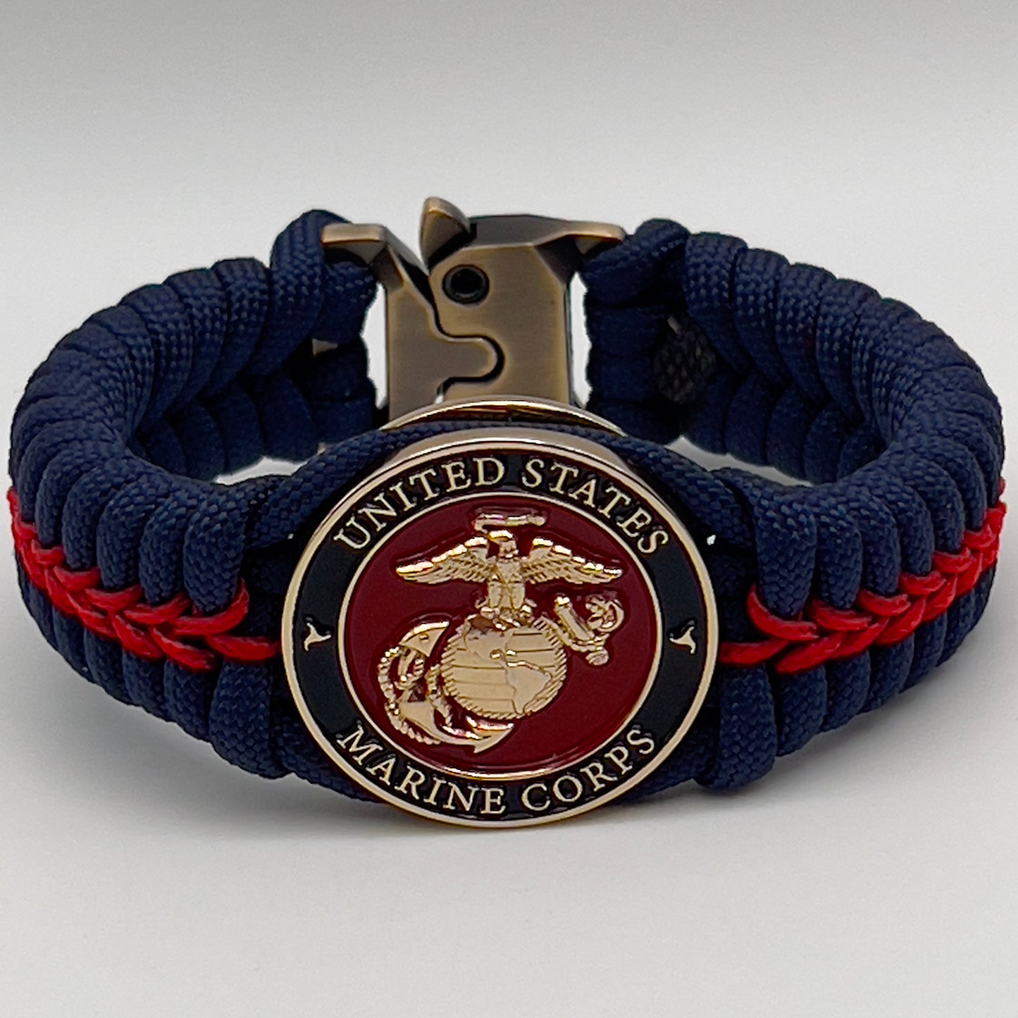 Thick, rigid and comfortable braided United States Marine Corps bracelet featuring a 24K gold plated USMC Eagle Globe and Anchor medallion, a gold Cobra style tactical buckle and woven withNavy Blue 550 paracord and Imperial Red micro cord.