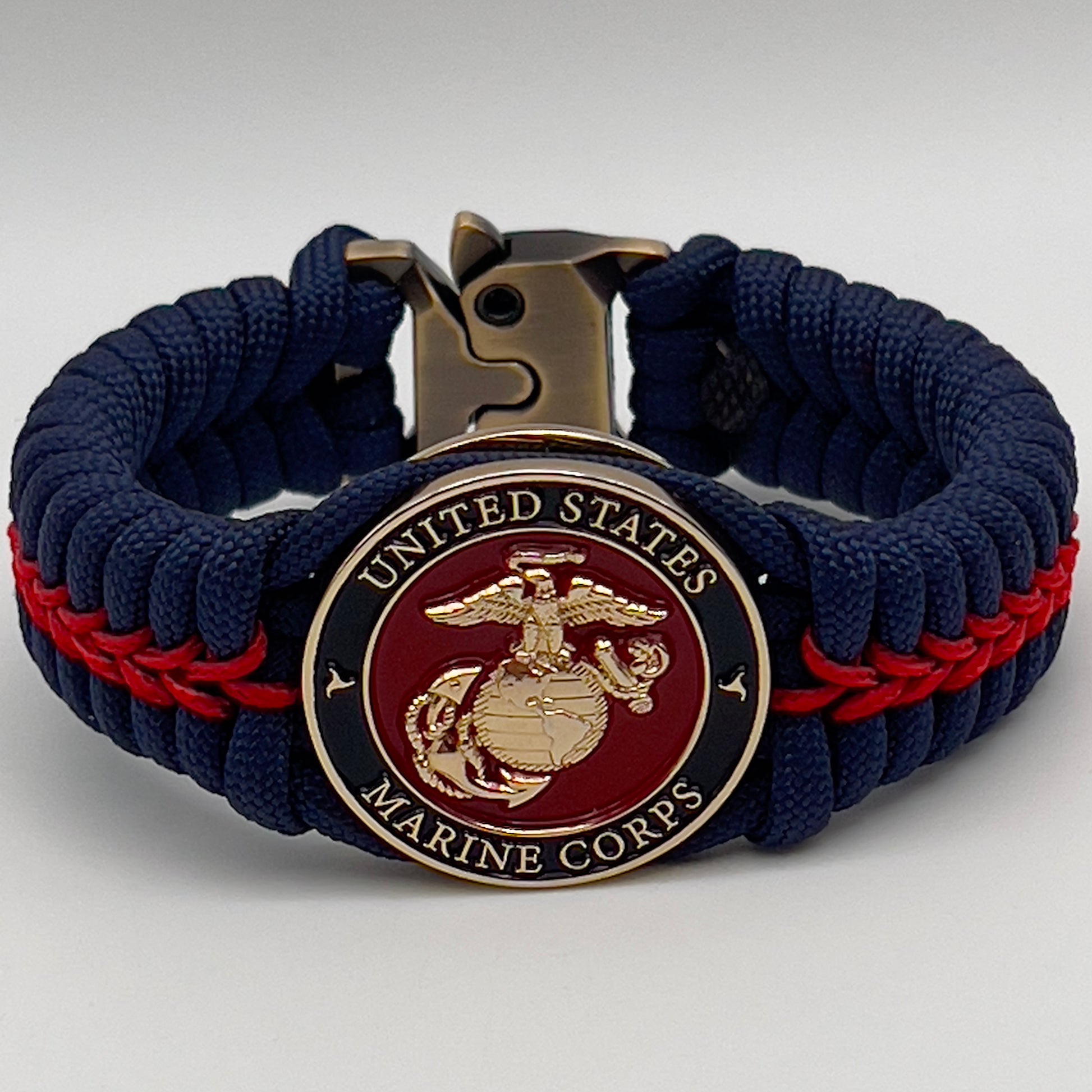 Thick, rigid and comfortable braided United States Marine Corps bracelet featuring a 24K gold plated USMC Eagle Globe and Anchor medallion, a gold Cobra style tactical buckle and woven withNavy Blue 550 paracord and Imperial Red micro cord.