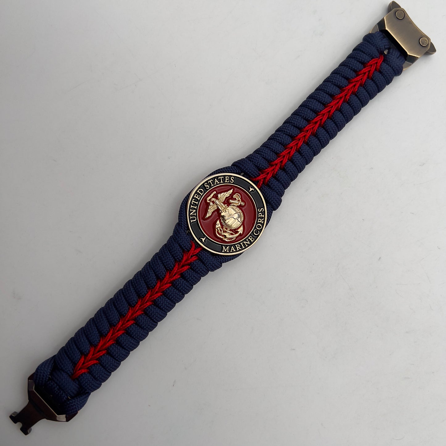 Thick, rigid and comfortable braided United States Marine Corps bracelet featuring a 24K gold plated USMC Eagle Globe and Anchor medallion, a gold Cobra style tactical buckle and woven withNavy Blue 550 paracord and Imperial Red micro cord.