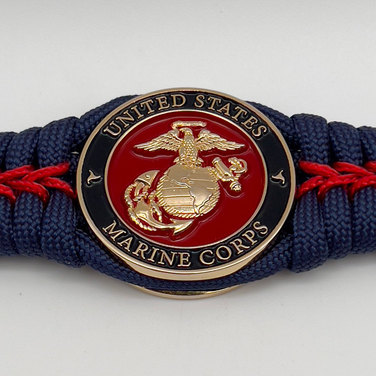 Thick, rigid and comfortable braided United States Marine Corps bracelet featuring a 24K gold plated USMC Eagle Globe and Anchor medallion, a gold Cobra style tactical buckle and woven withNavy Blue 550 paracord and Imperial Red micro cord.