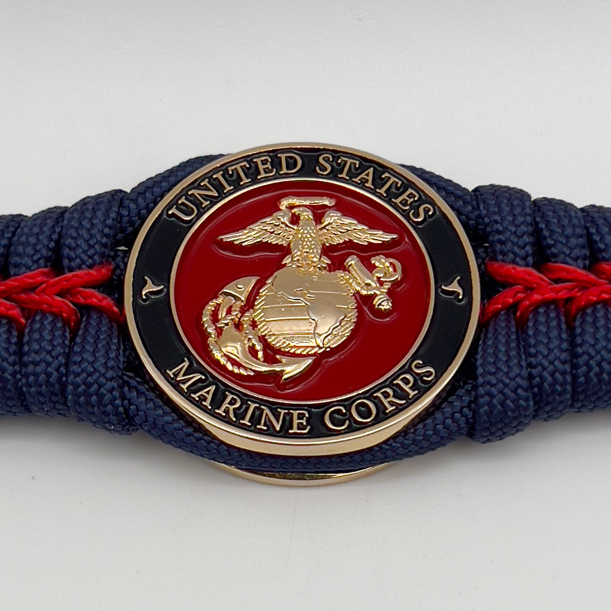 Thick, rigid and comfortable braided United States Marine Corps bracelet featuring a 24K gold plated USMC Eagle Globe and Anchor medallion, a gold Cobra style tactical buckle and woven withNavy Blue 550 paracord and Imperial Red micro cord.