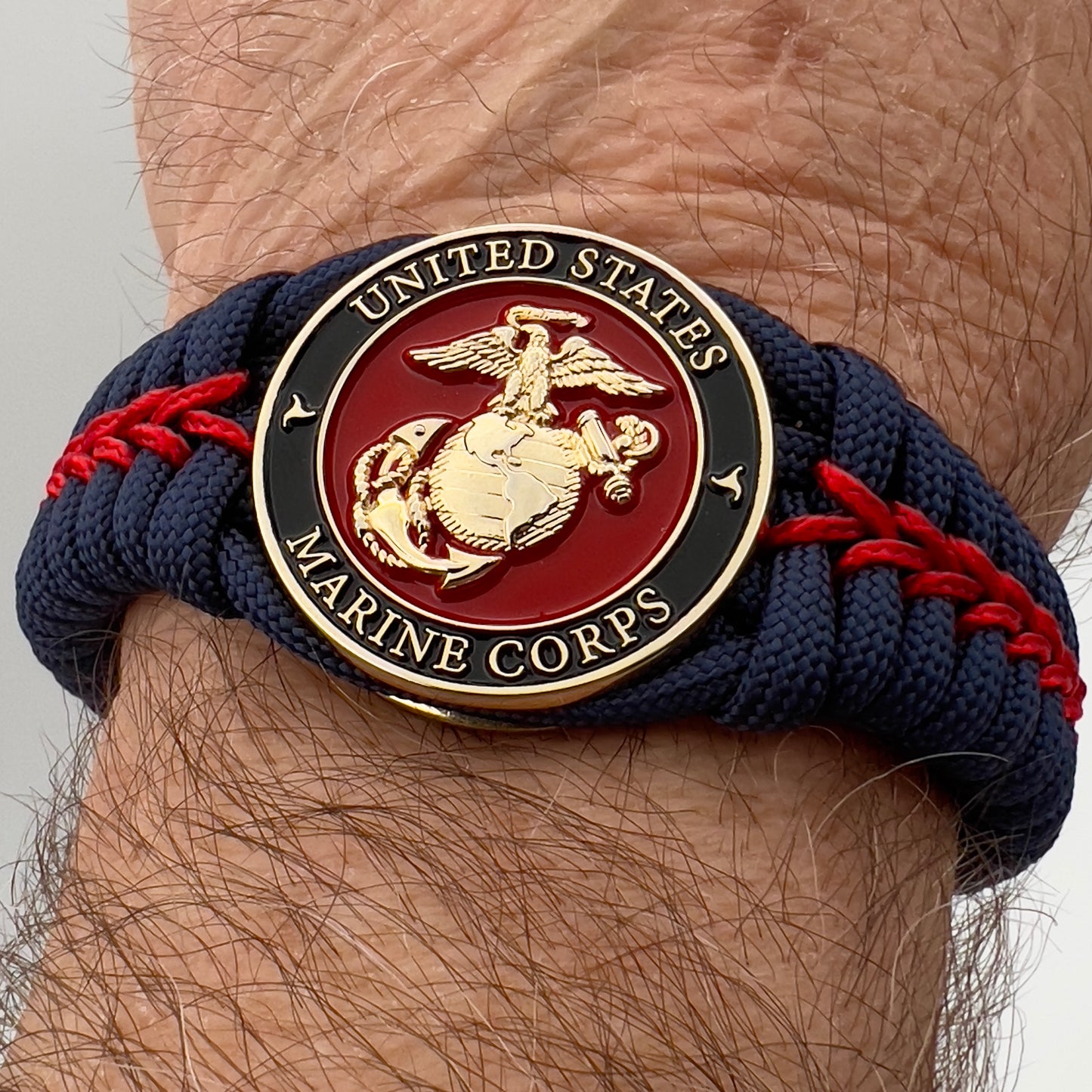 Thick, rigid and comfortable braided United States Marine Corps bracelet featuring a 24K gold plated USMC Eagle Globe and Anchor medallion, a gold Cobra style tactical buckle and woven withNavy Blue 550 paracord and Imperial Red micro cord.