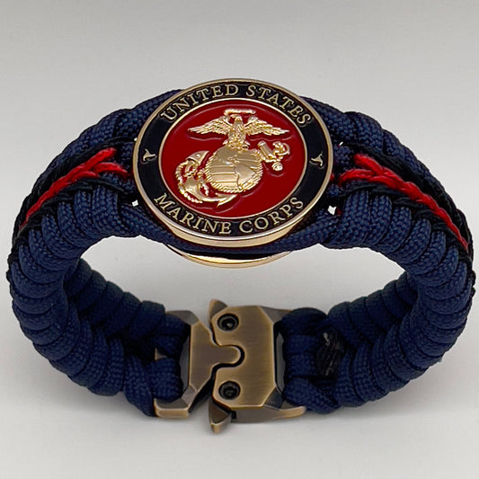 Thick, rigid and comfortable braided United States Marine Corps bracelet featuring a 24K gold plated USMC Eagle Globe and Anchor medallion, a gold Cobra style tactical buckle and woven with Navy Blue 550 paracord and Imperial Red and Black micro cord.
