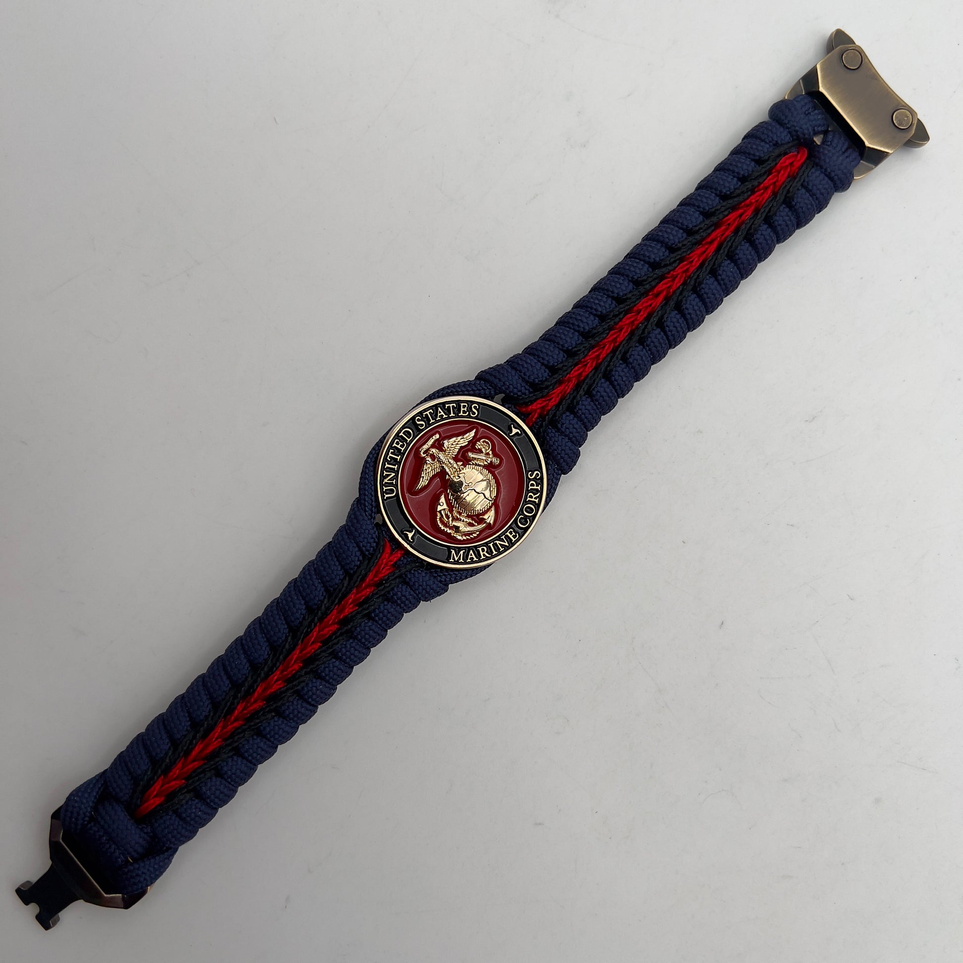 Thick, rigid and comfortable braided United States Marine Corps bracelet featuring a 24K gold plated USMC Eagle Globe and Anchor medallion, a gold Cobra style tactical buckle and woven with Navy Blue 550 paracord and Imperial Red and Black micro cord.