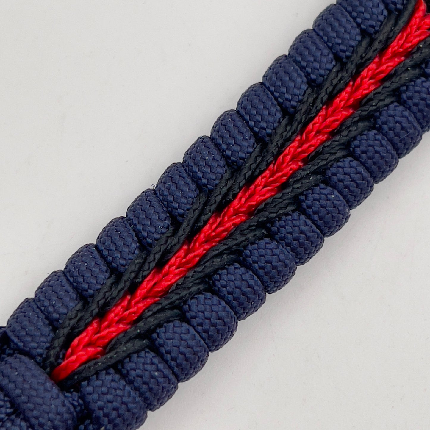 Thick, rigid and comfortable braided United States Marine Corps bracelet featuring a 24K gold plated USMC Eagle Globe and Anchor medallion, a gold Cobra style tactical buckle and woven with Navy Blue 550 paracord and Imperial Red and Black micro cord.