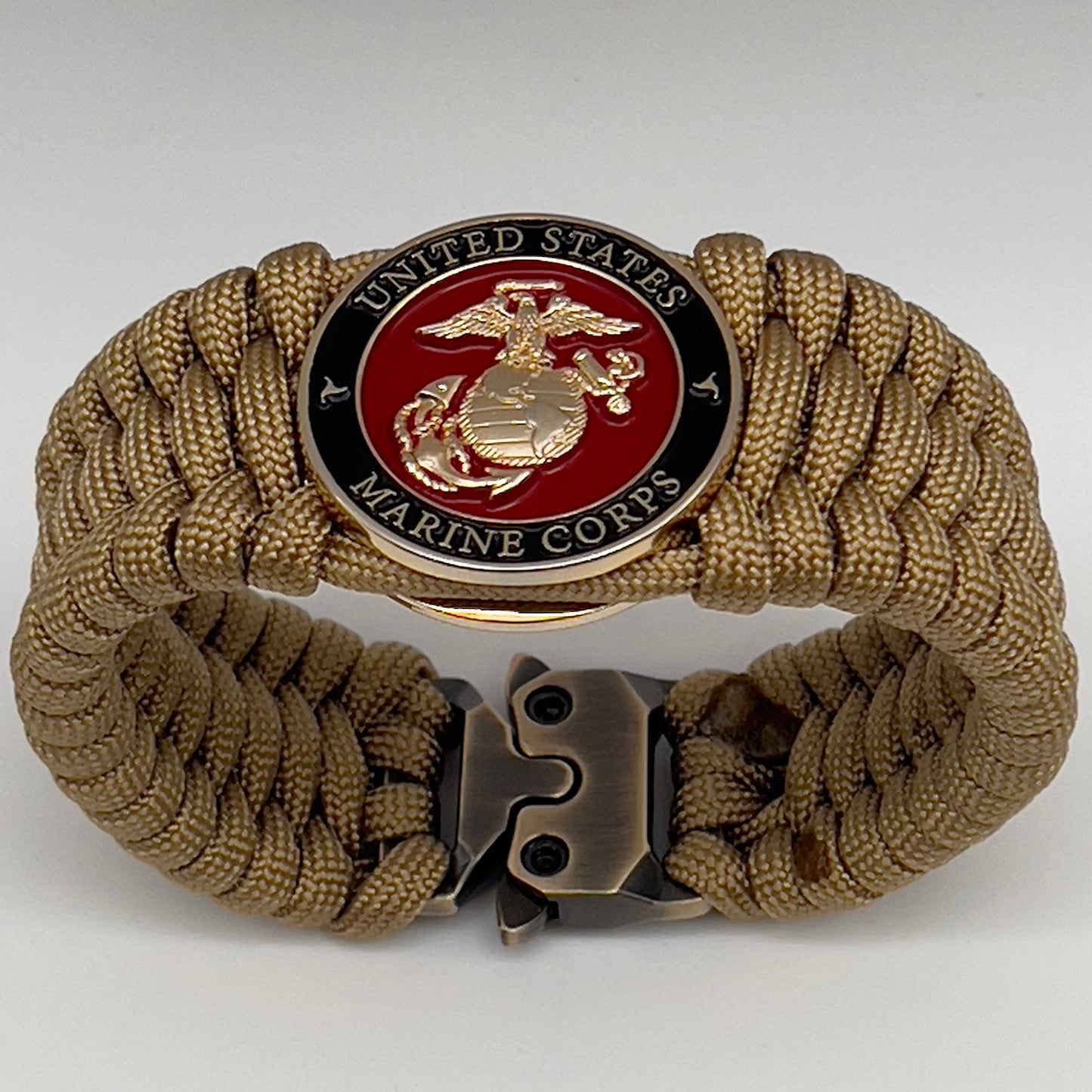 Thick, wide, rigid and comfortable braided United States Marine Corps bracelet featuring a 24K gold plated USMC Eagle Globe and Anchor medallion, a gold Cobra style tactical buckle and woven with gold 550 paracord.