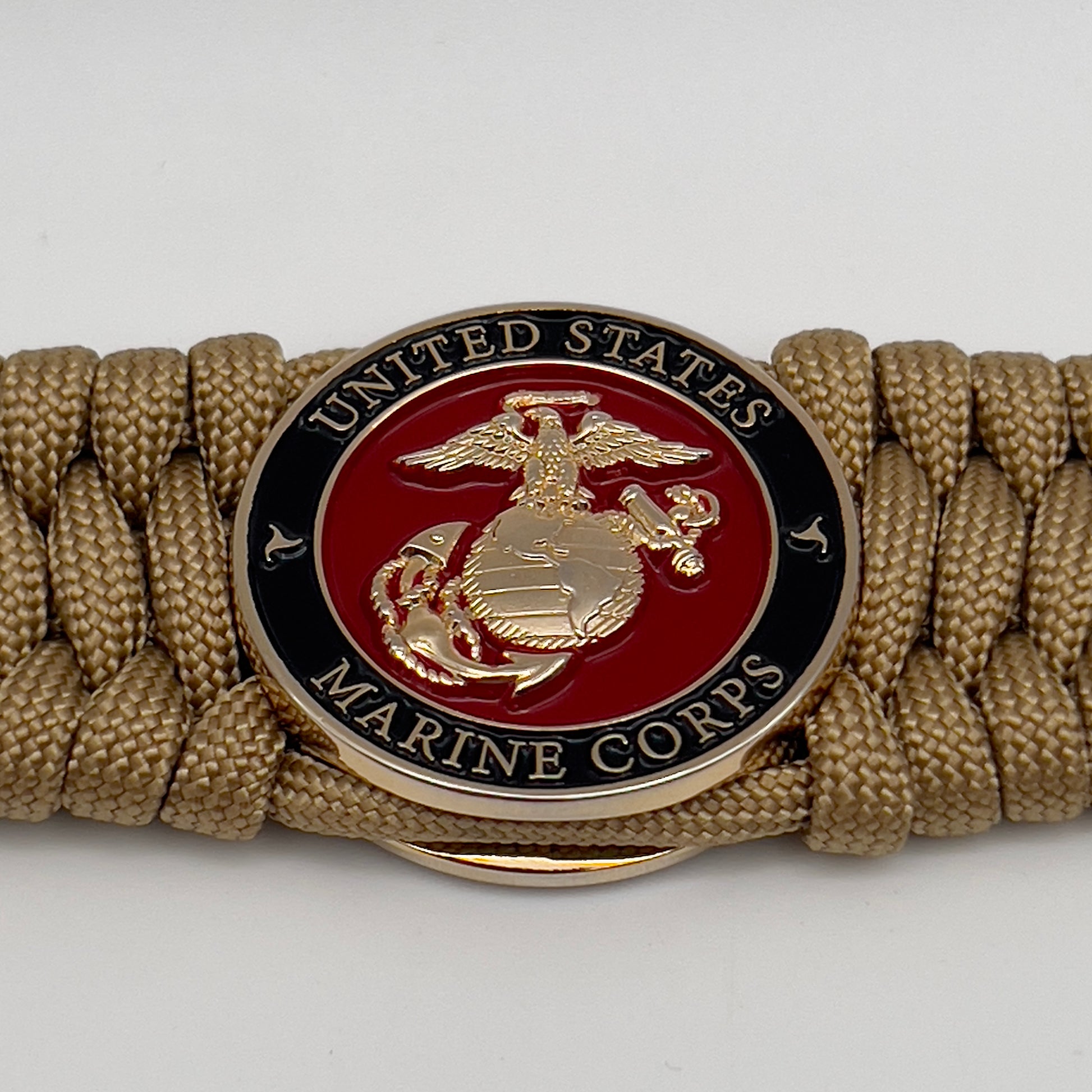 Thick, wide, rigid and comfortable braided United States Marine Corps bracelet featuring a 24K gold plated USMC Eagle Globe and Anchor medallion, a gold Cobra style tactical buckle and woven with gold 550 paracord.