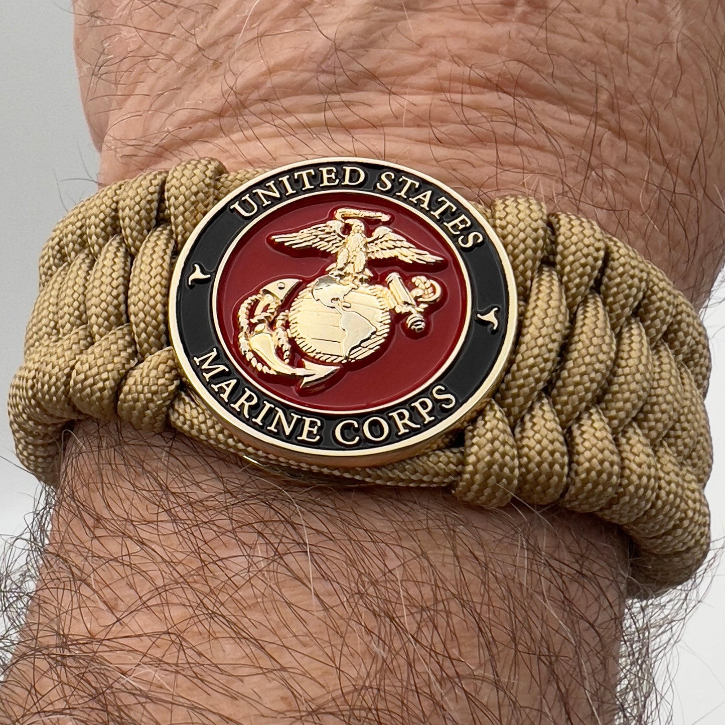 Thick, wide, rigid and comfortable braided United States Marine Corps bracelet featuring a 24K gold plated USMC Eagle Globe and Anchor medallion, a gold Cobra style tactical buckle and woven with gold 550 paracord.