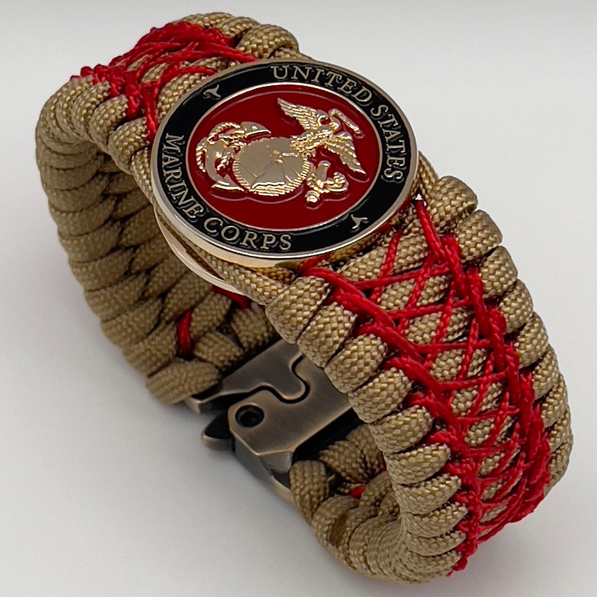 Thick, wide, rigid and comfortable braided United States Marine Corps bracelet featuring a 24K gold plated USMC Eagle Globe and Anchor medallion, a gold Cobra style tactical buckle and woven with gold 550 paracord and Imperial Red nano and micro cord.