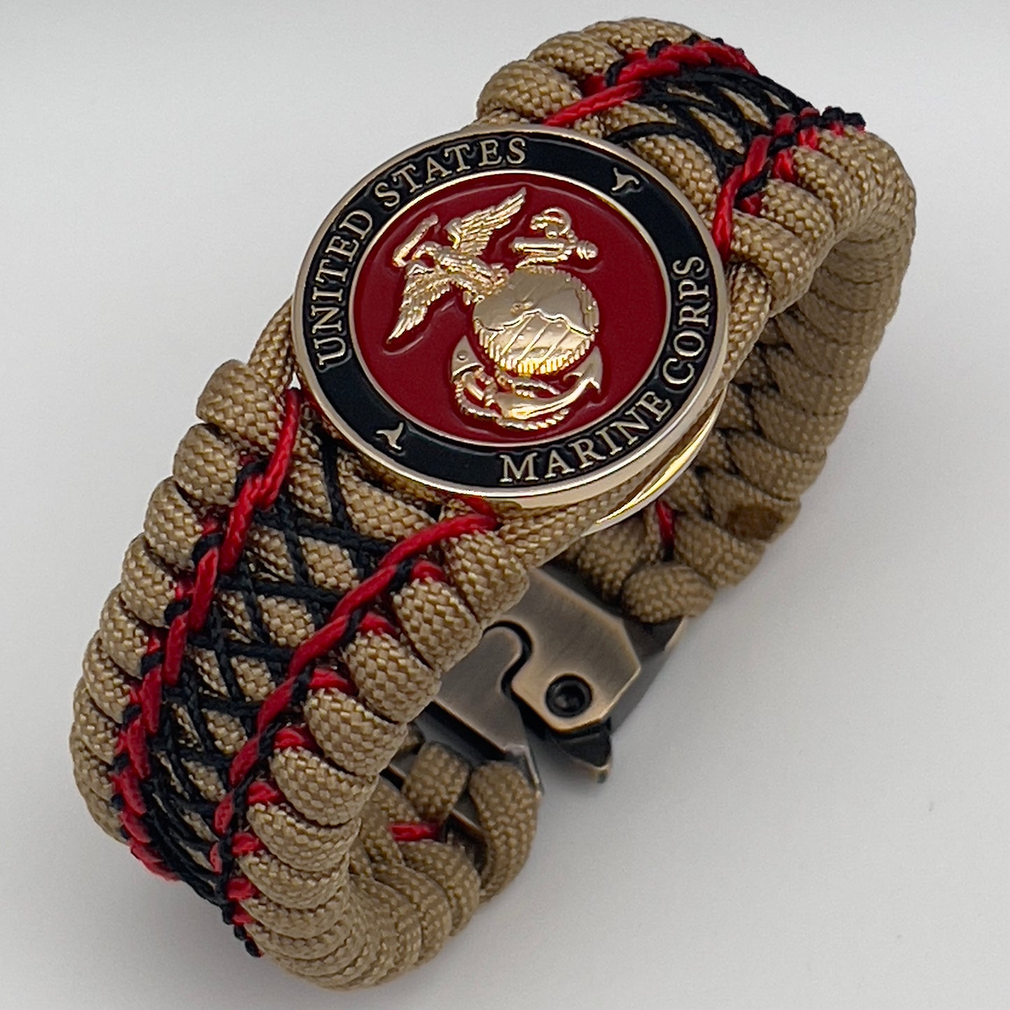 Thick, wide, rigid and comfortable braided United States Marine Corps bracelet featuring a 24K gold plated USMC Eagle Globe and Anchor medallion, a gold Cobra style tactical buckle and woven with gold 550 paracord and Imperial Red micro and black nano cord.