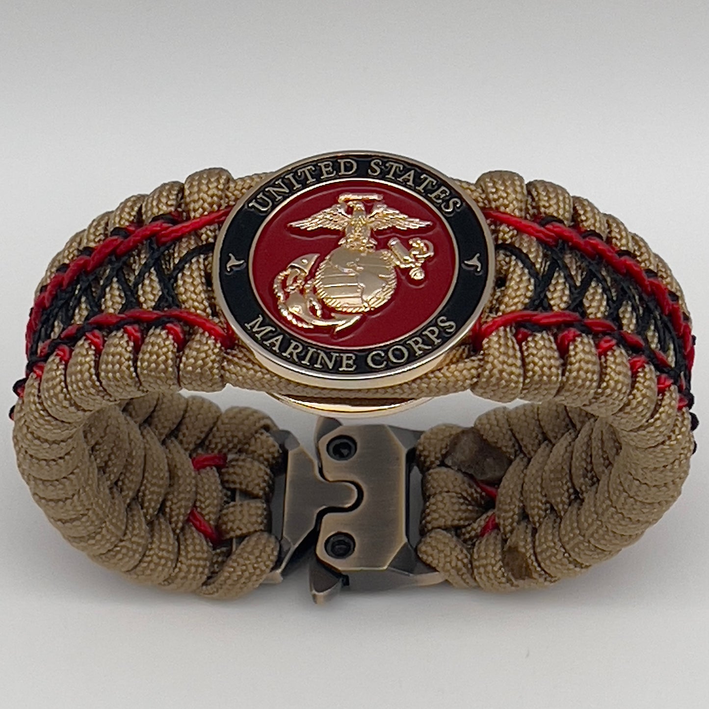 Thick, wide, rigid and comfortable braided United States Marine Corps bracelet featuring a 24K gold plated USMC Eagle Globe and Anchor medallion, a gold Cobra style tactical buckle and woven with gold 550 paracord and Imperial Red micro and black nano cord.