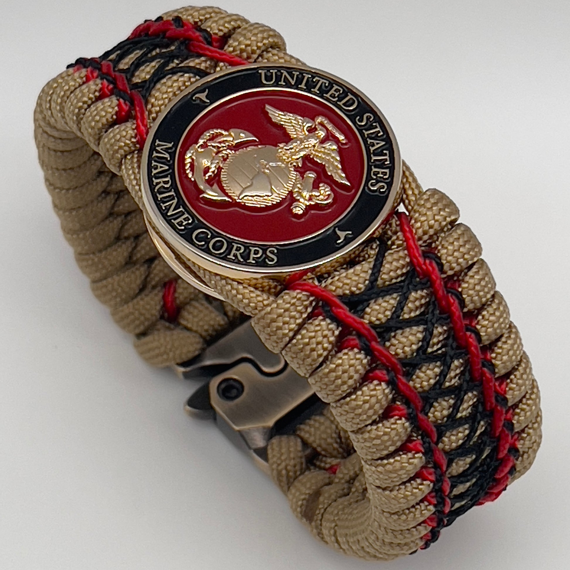 Thick, wide, rigid and comfortable braided United States Marine Corps bracelet featuring a 24K gold plated USMC Eagle Globe and Anchor medallion, a gold Cobra style tactical buckle and woven with gold 550 paracord and Imperial Red micro and black nano cord.