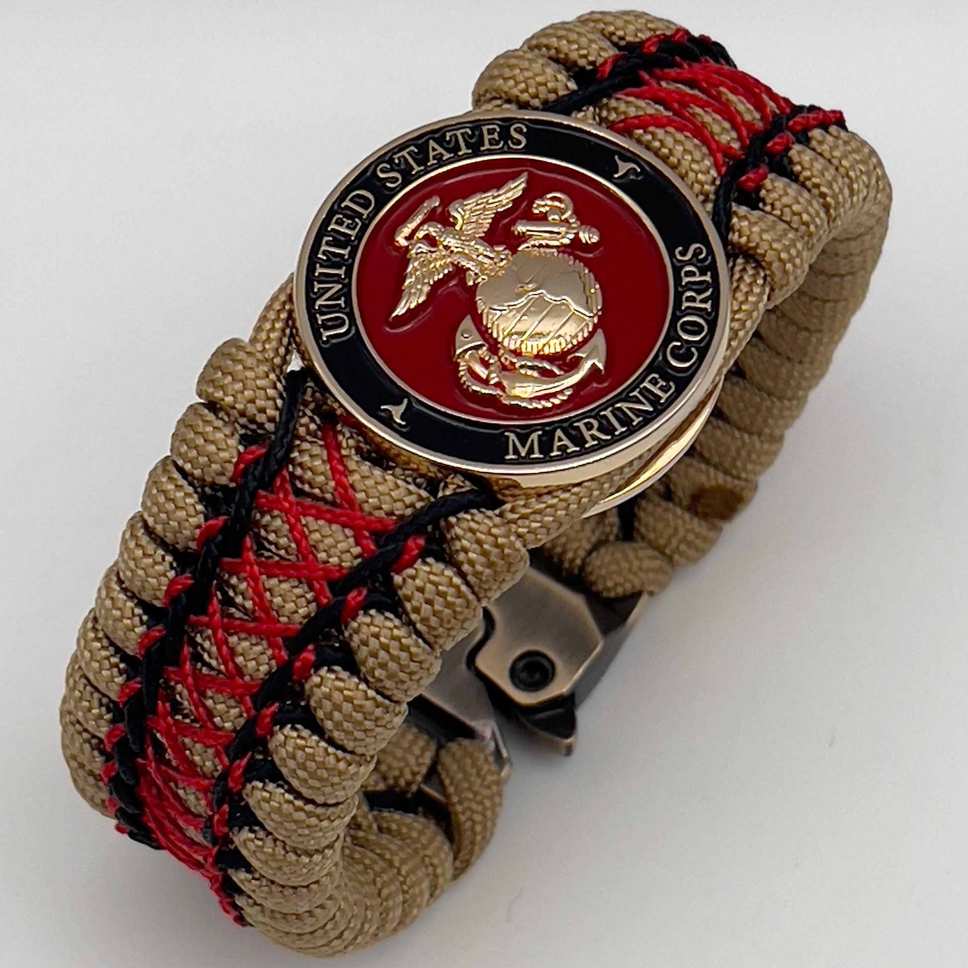Thick, wide, rigid and comfortable braided United States Marine Corps bracelet featuring a 24K gold plated USMC Eagle Globe and Anchor medallion, a gold Cobra style tactical buckle and woven with gold 550 paracord and Imperial Red micro and black nano cord.