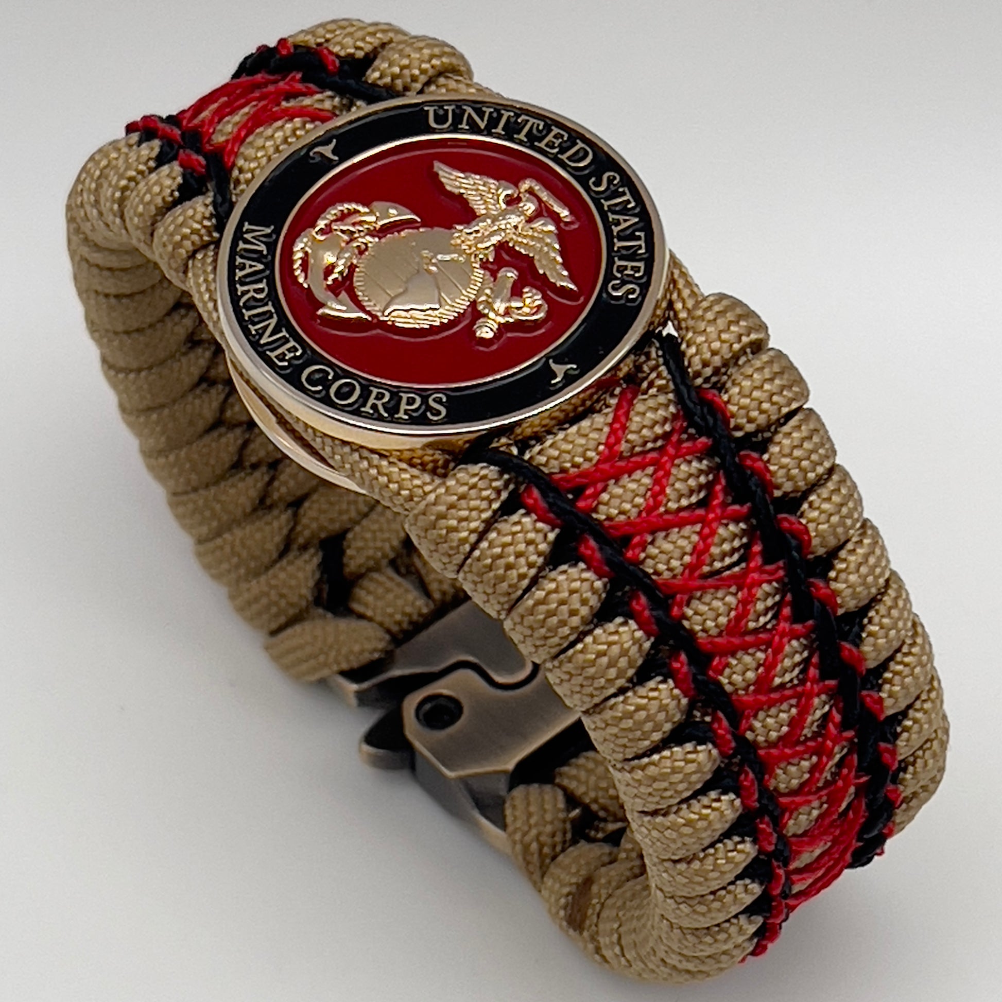 Thick, wide, rigid and comfortable braided United States Marine Corps bracelet featuring a 24K gold plated USMC Eagle Globe and Anchor medallion, a gold Cobra style tactical buckle and woven with gold 550 paracord and Imperial Red micro and black nano cord.