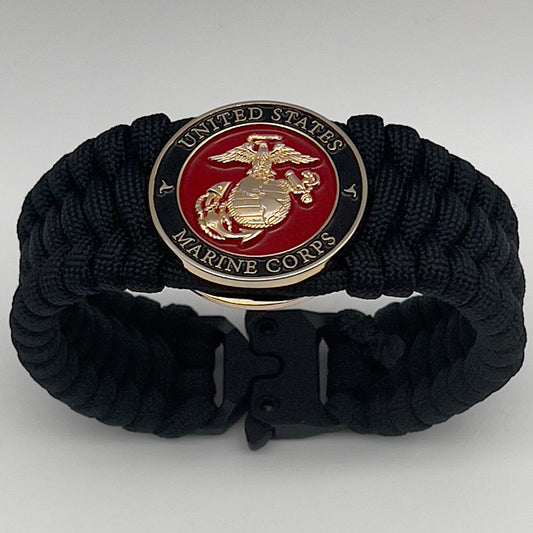 Thick, wide, rigid and comfortable braided United States Marine Corps bracelet featuring a 24K gold plated USMC Eagle Globe and Anchor medallion, a black Cobra style tactical buckle and woven with black 550 paracord.