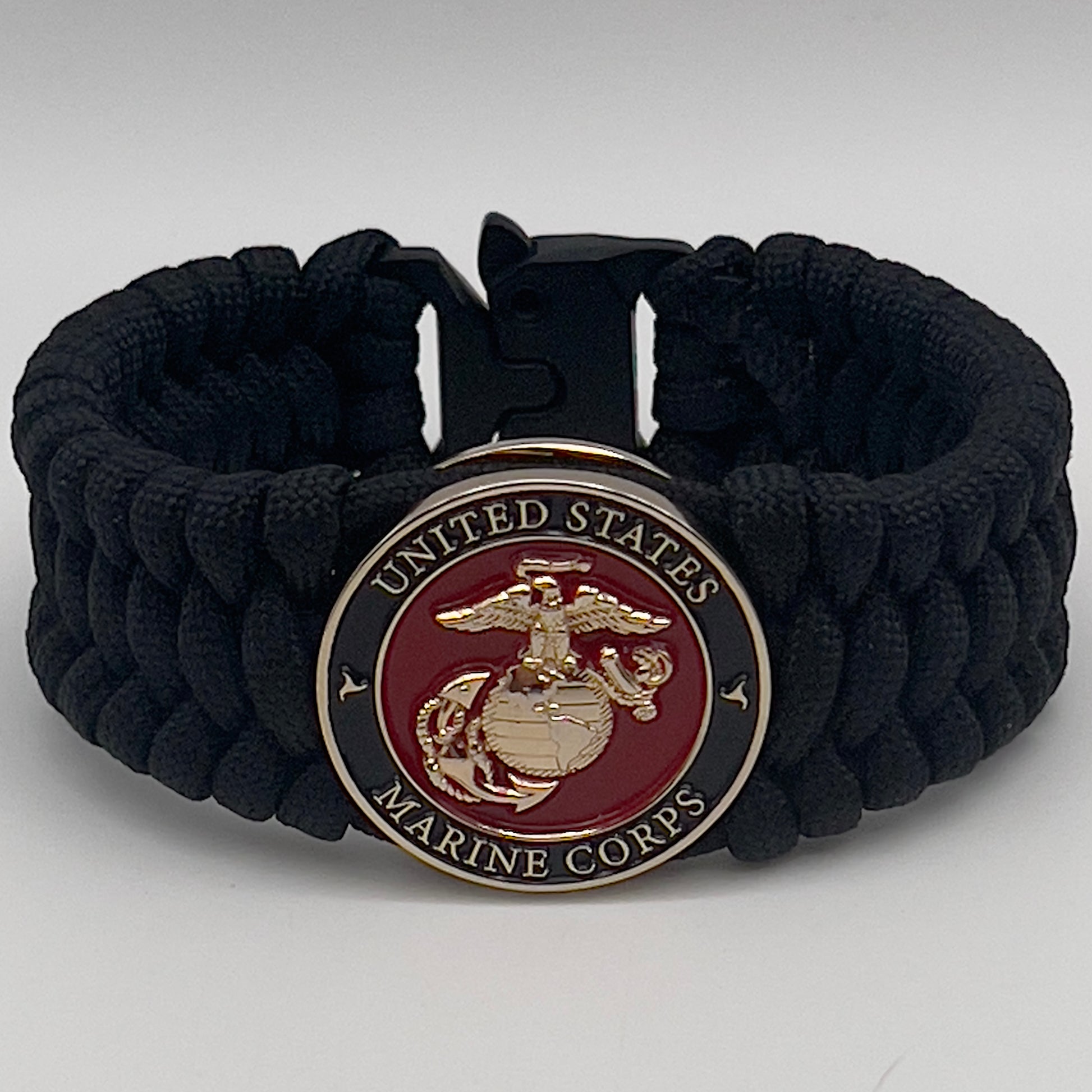 Thick, wide, rigid and comfortable braided United States Marine Corps bracelet featuring a 24K gold plated USMC Eagle Globe and Anchor medallion, a black Cobra style tactical buckle and woven with black 550 paracord.