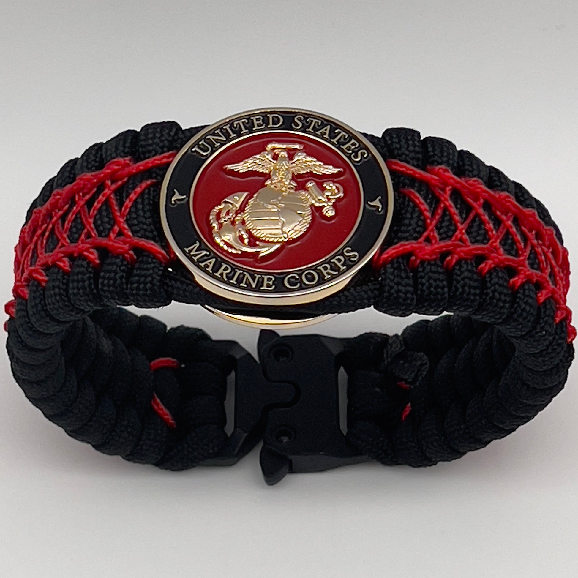 Thick, wide, rigid and comfortable braided United States Marine Corps bracelet featuring a 24K gold plated USMC Eagle Globe and Anchor medallion, a black Cobra style tactical buckle and woven with black 550 paracord and Imperial Red nano and micro cord.