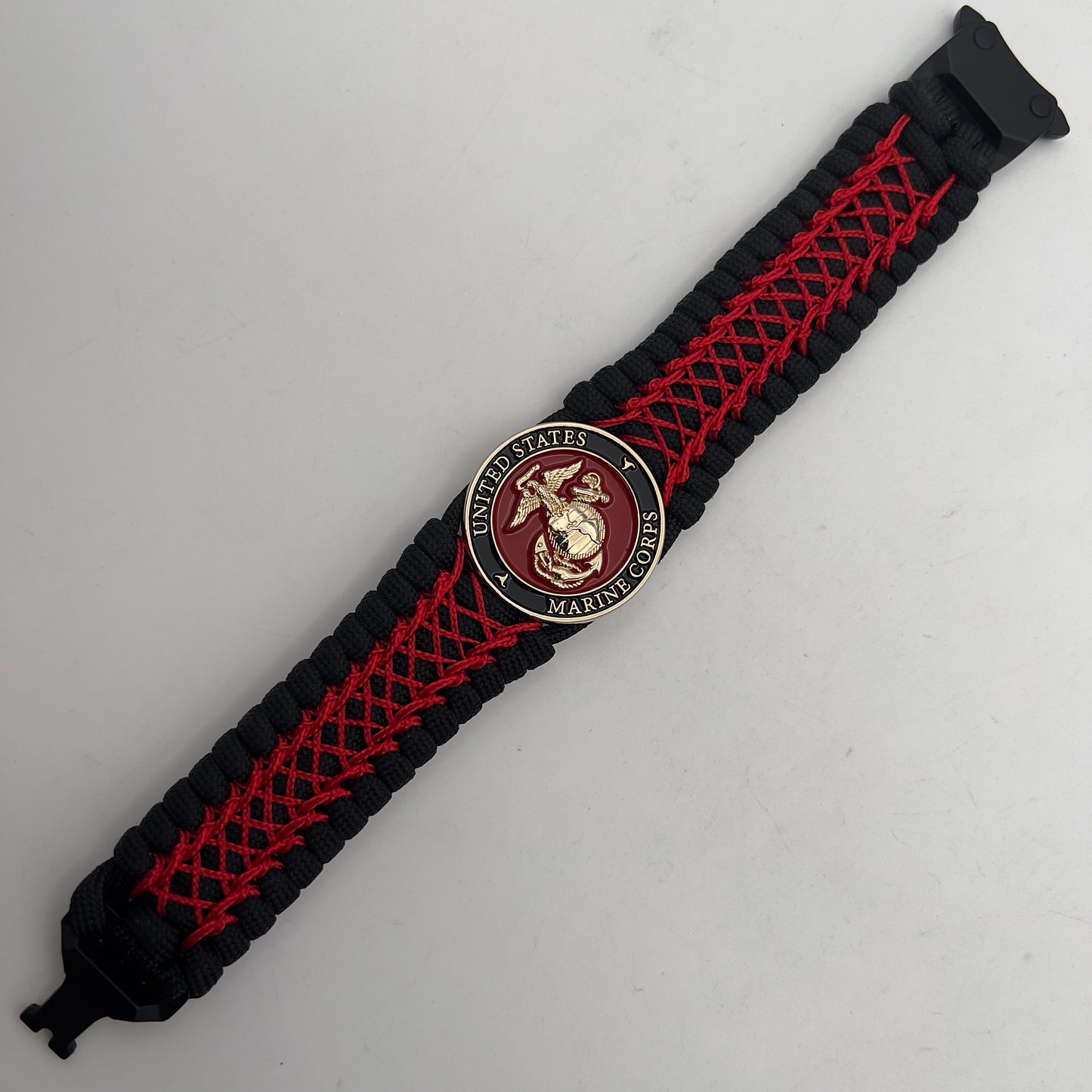 Thick, wide, rigid and comfortable braided United States Marine Corps bracelet featuring a 24K gold plated USMC Eagle Globe and Anchor medallion, a black Cobra style tactical buckle and woven with black 550 paracord and Imperial Red nano and micro cord.